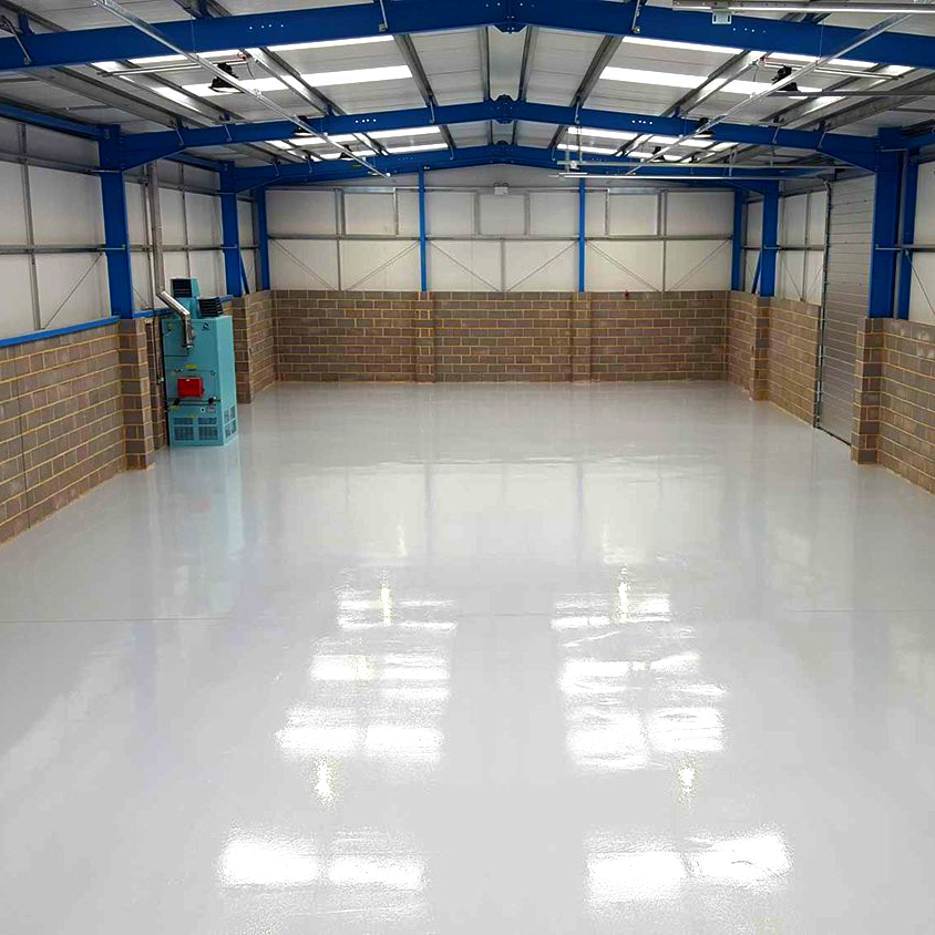 A large warehouse with a white floor and brick walls.