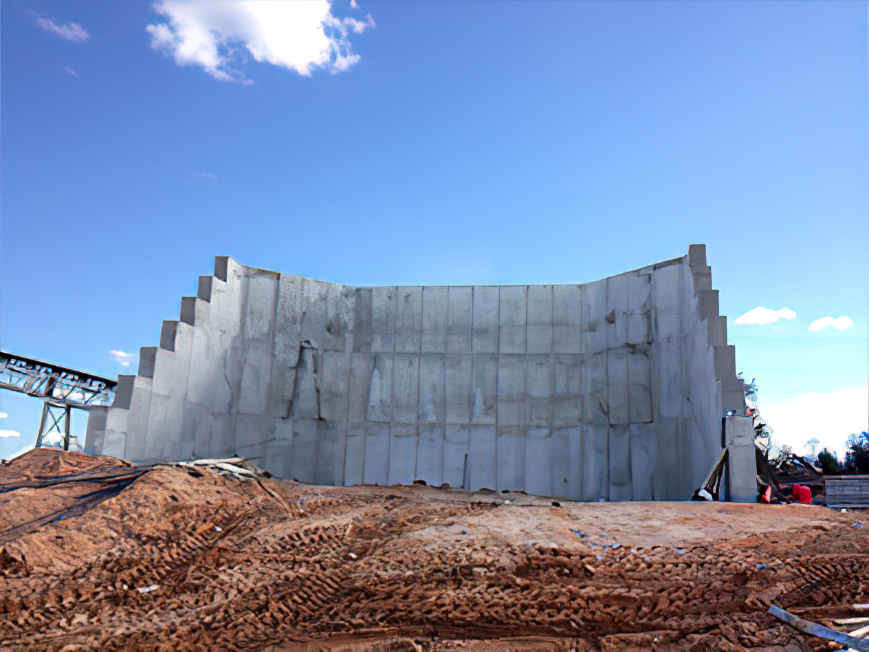 A large concrete wall is being built in a dirt field