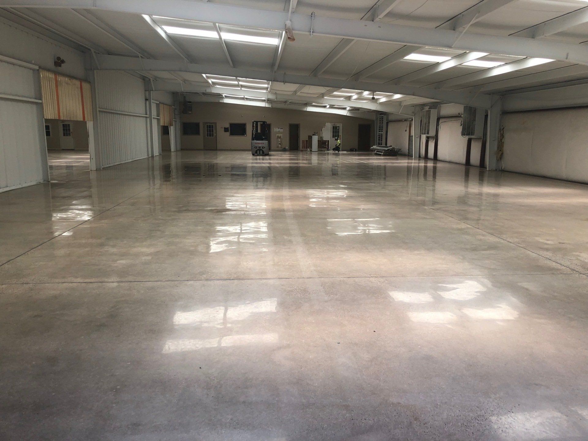 A large empty warehouse with a shiny concrete floor and white walls.