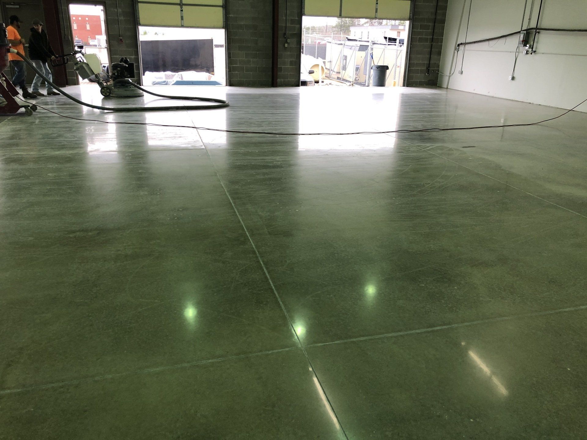 A large warehouse with a shiny concrete floor and a vacuum cleaner.