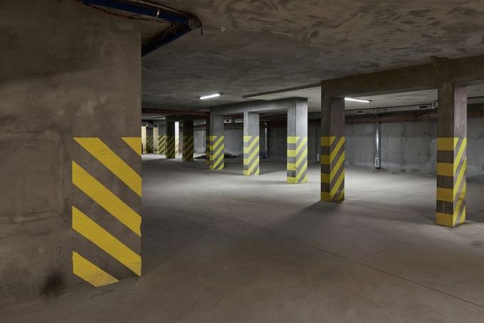 Empty concrete parking garage with striped support pillars and overhead lighting
