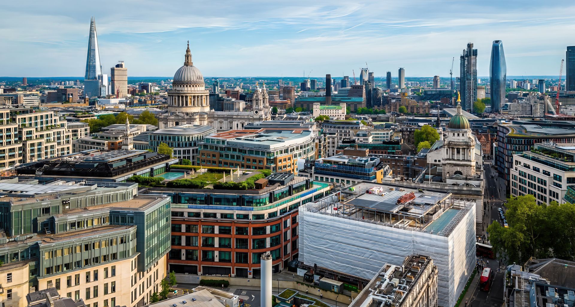 City skyline with modern buildings and historic domes under a bright blue sky