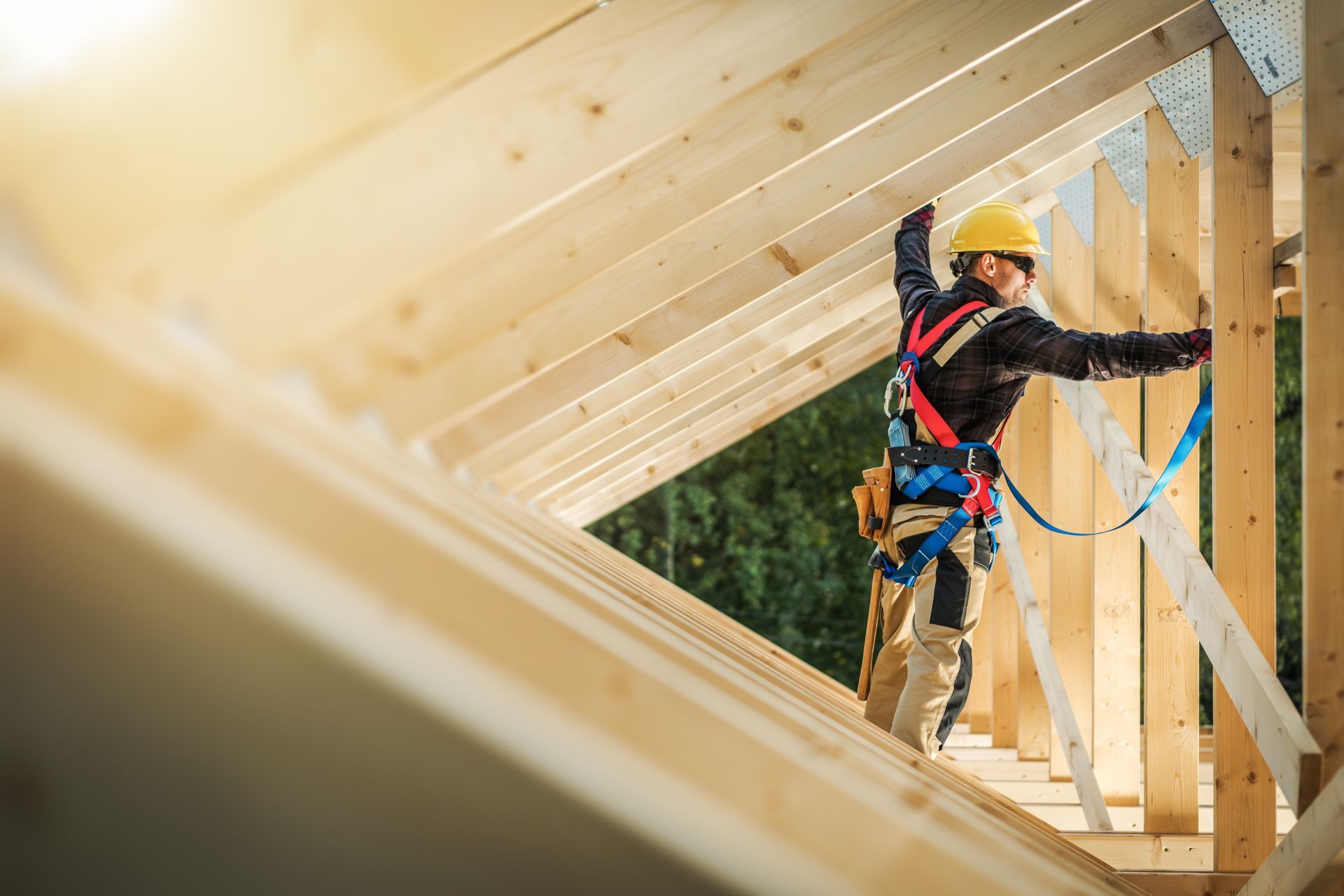 Construction worker in hard hat standing on wooden framing inside a house under construction