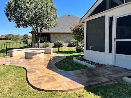 Backyard patio with stone walkway, built-in bench, and landscaped lawn in Denton TX