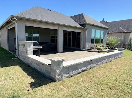 Backyard patio with low stone wall and covered seating area in Denton TX