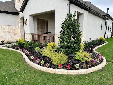 Landscaped front yard with curved stone border and flowering shrubs in Denton TX