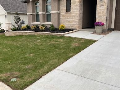 Brick house front yard with green lawn and concrete driveway in Denton TX