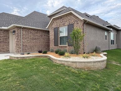 Brick house with curved stone garden bed and dark mulch landscaping
