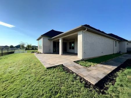 Single-story home with covered patio, paved walkway, and green lawn in Denton TX