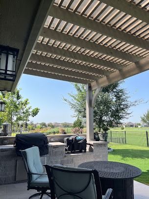 Covered pergola patio with wicker chairs overlooking green yard in Denton area