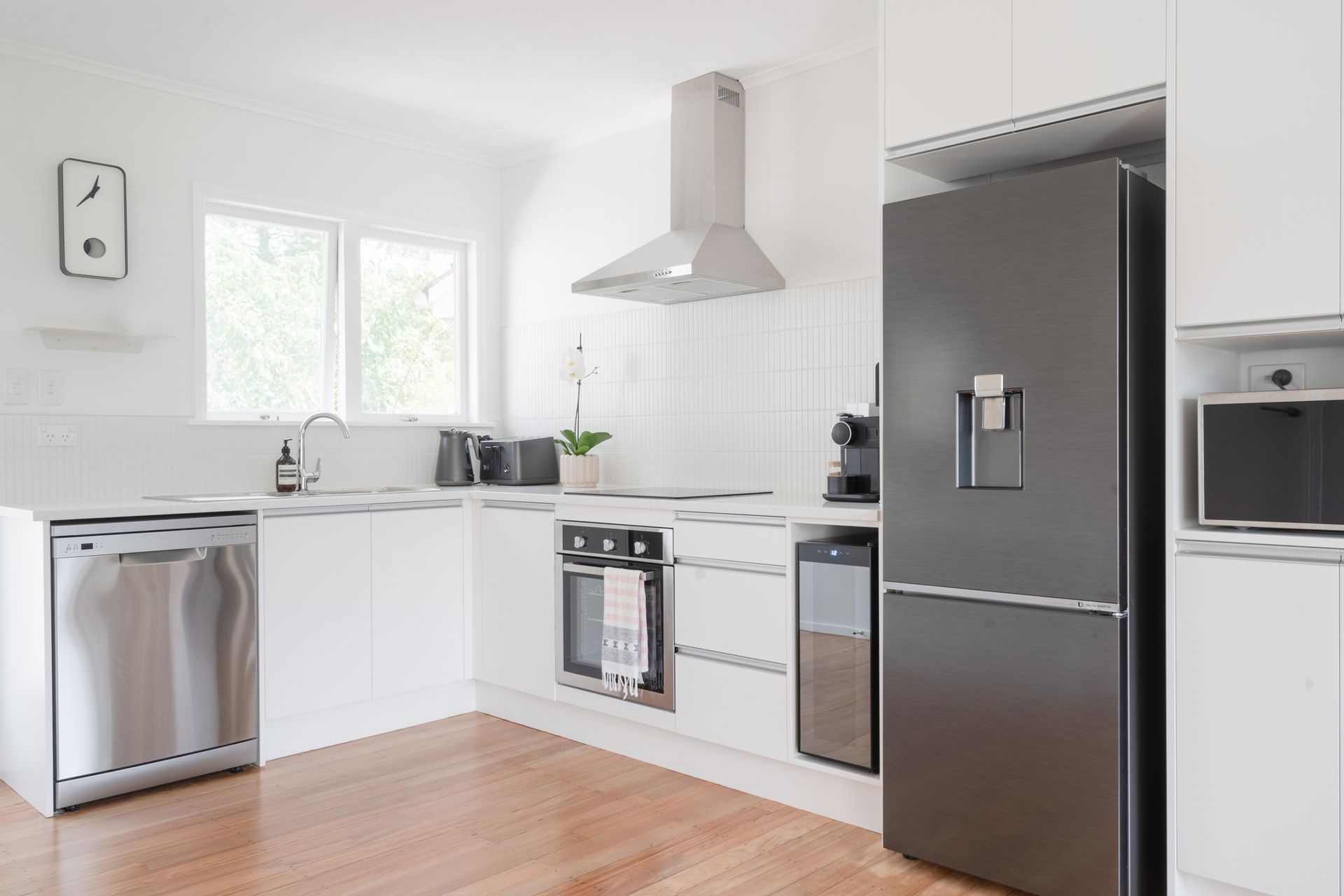 A kitchen with white cabinets , stainless steel appliances and a black refrigerator.