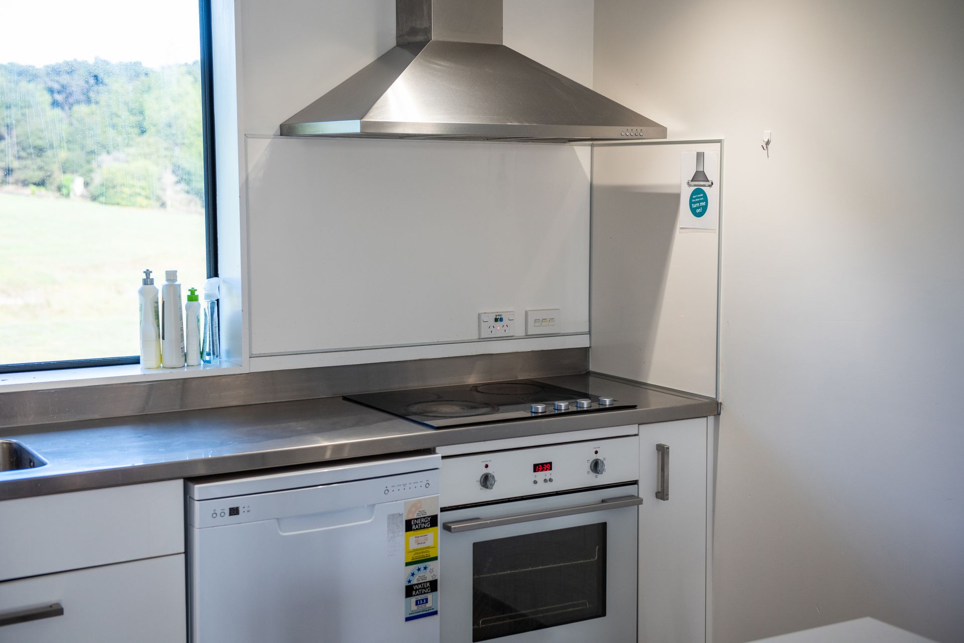 A kitchen with white cabinets , a stove , a dishwasher , and a window.