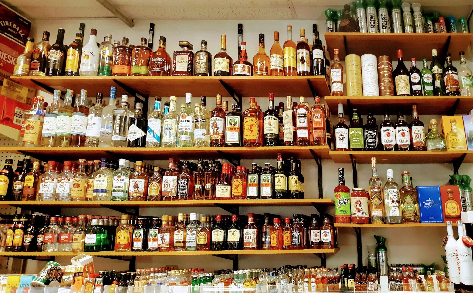 Shelves filled with bottles of liquor including one that says ' smirnoff ' on it