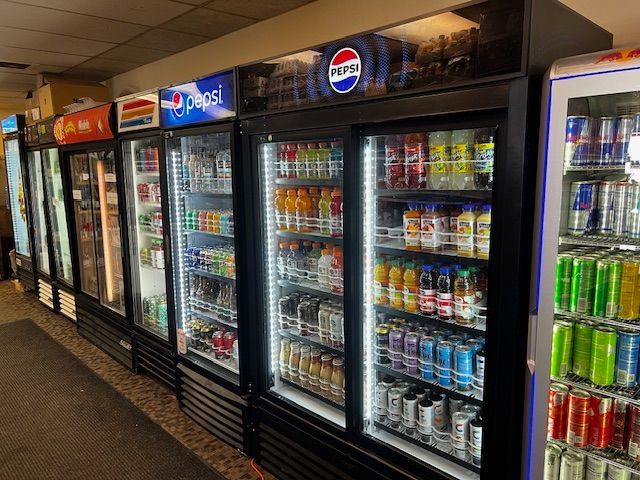 A row of refrigerators filled with sodas and beverages in a store.