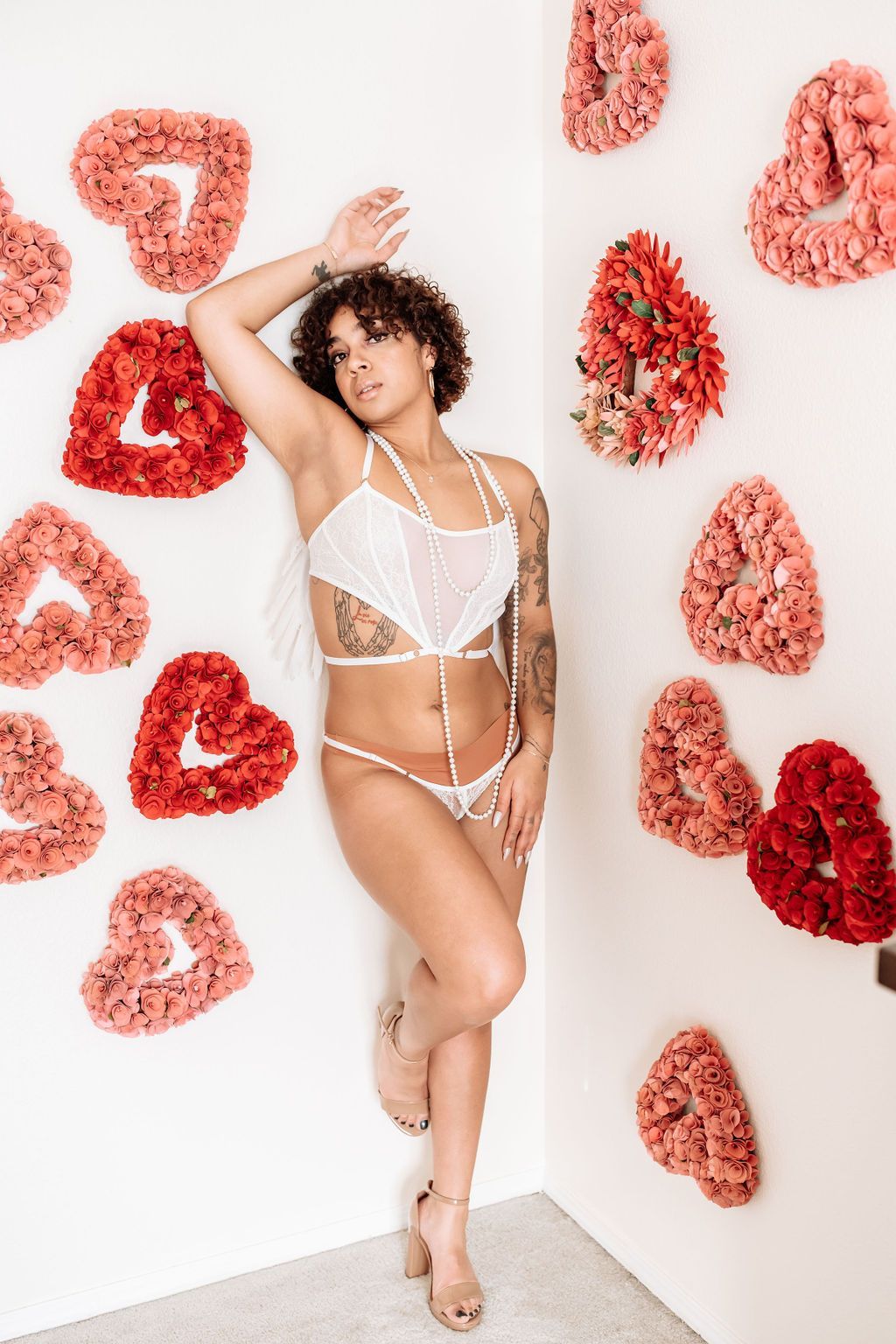 A woman in lingerie is standing in a room with hearts on the wall.
