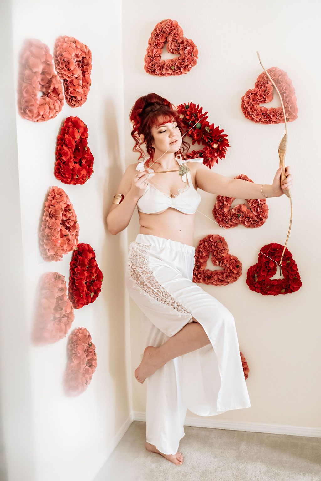 A woman is standing in front of a wall with hearts made of flowers.