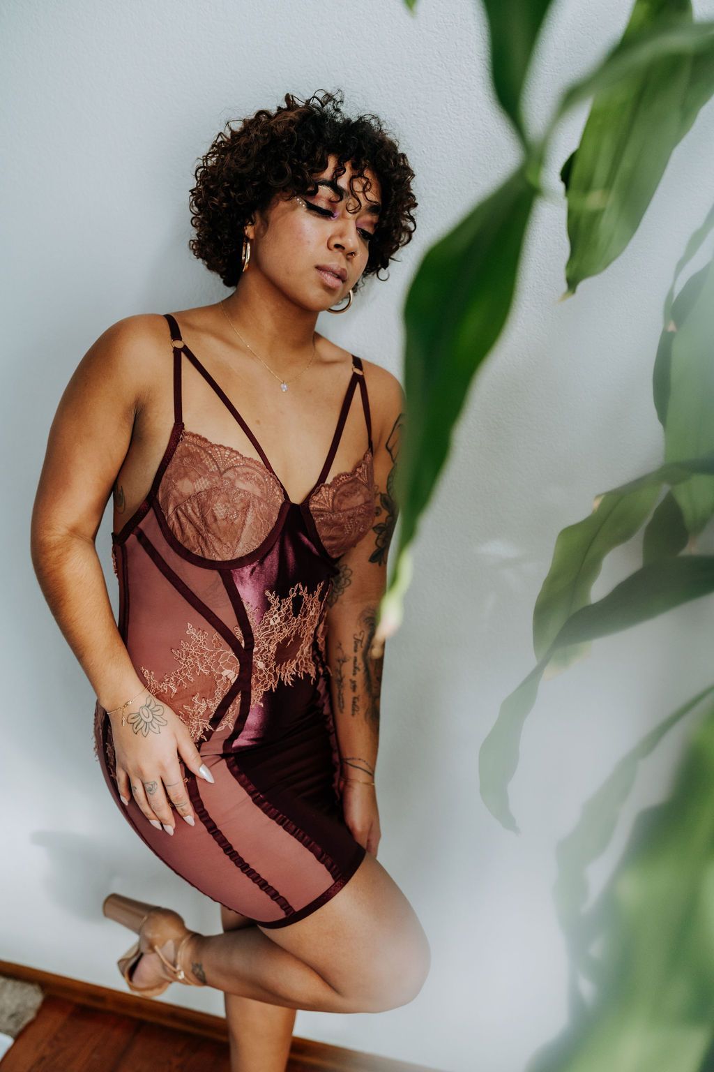A woman in a lingerie dress is standing next to a plant.