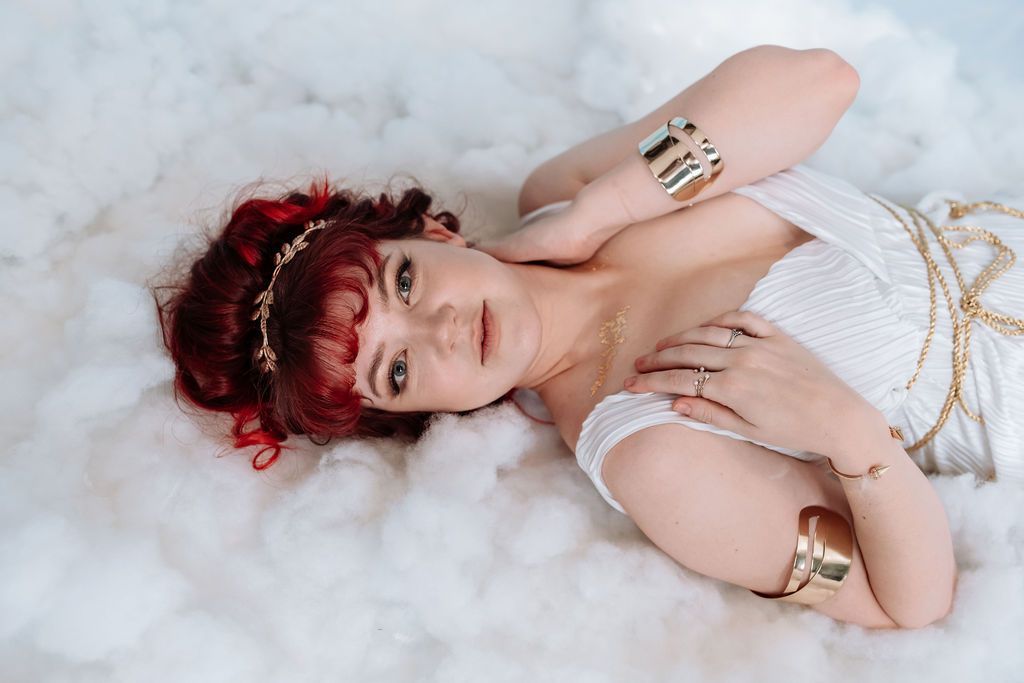 A woman in a white dress is laying on a cloud.