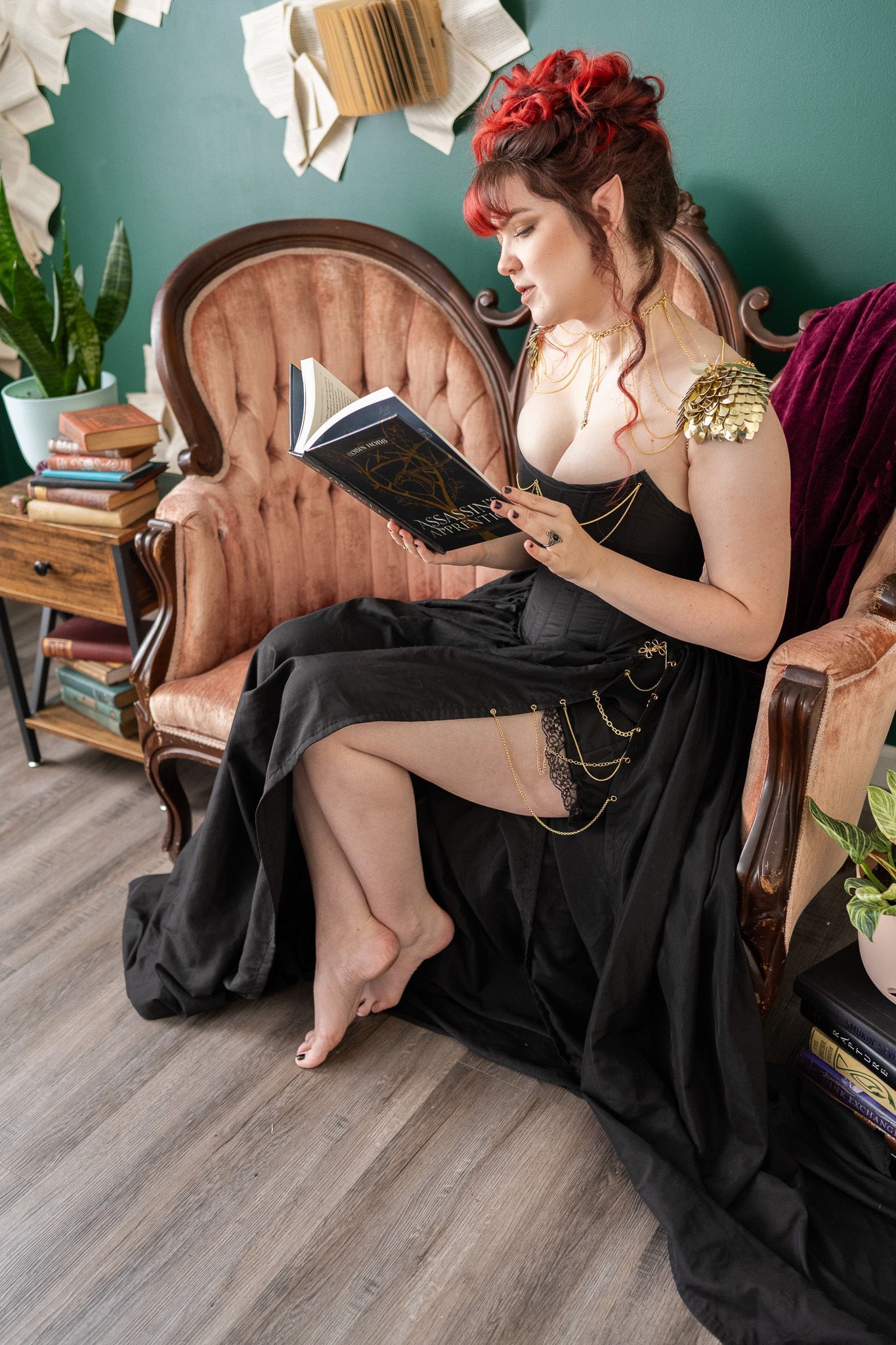 A woman in a black dress is sitting in a chair reading a book.
