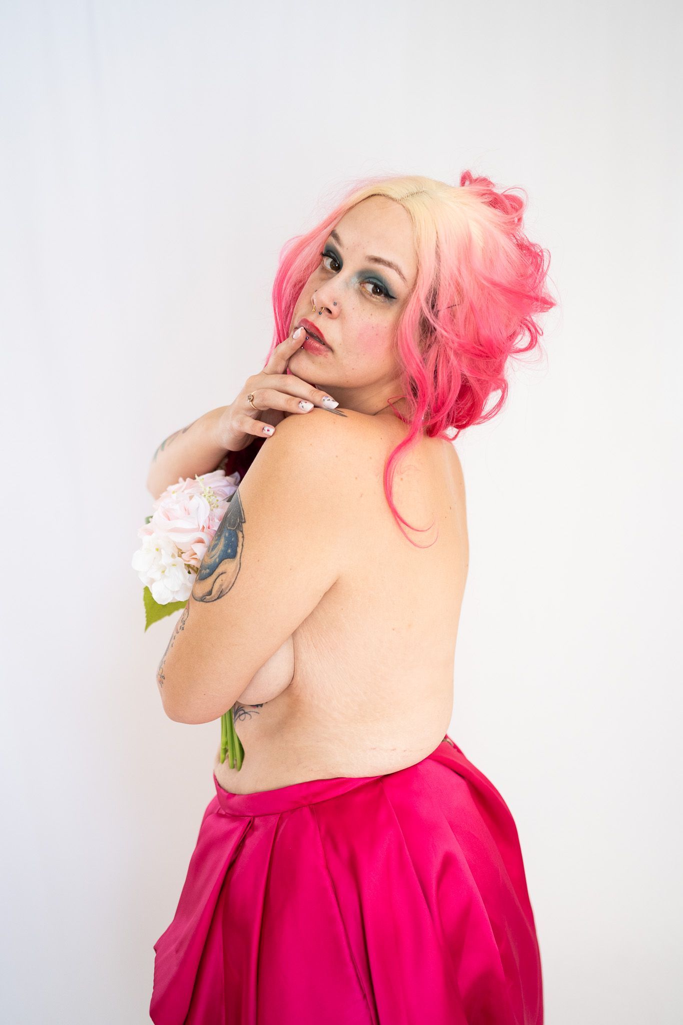 a woman holding flowers with her back and side breast showing. 