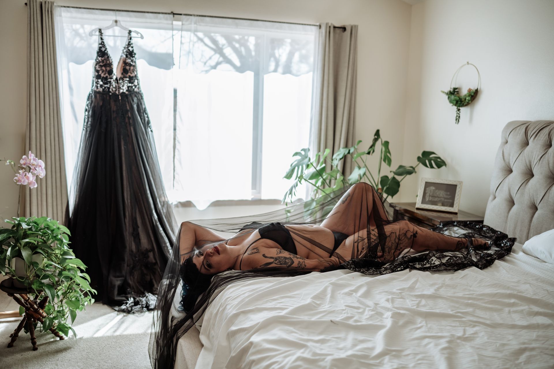 A woman in lingerie is laying on a bed in a bedroom.