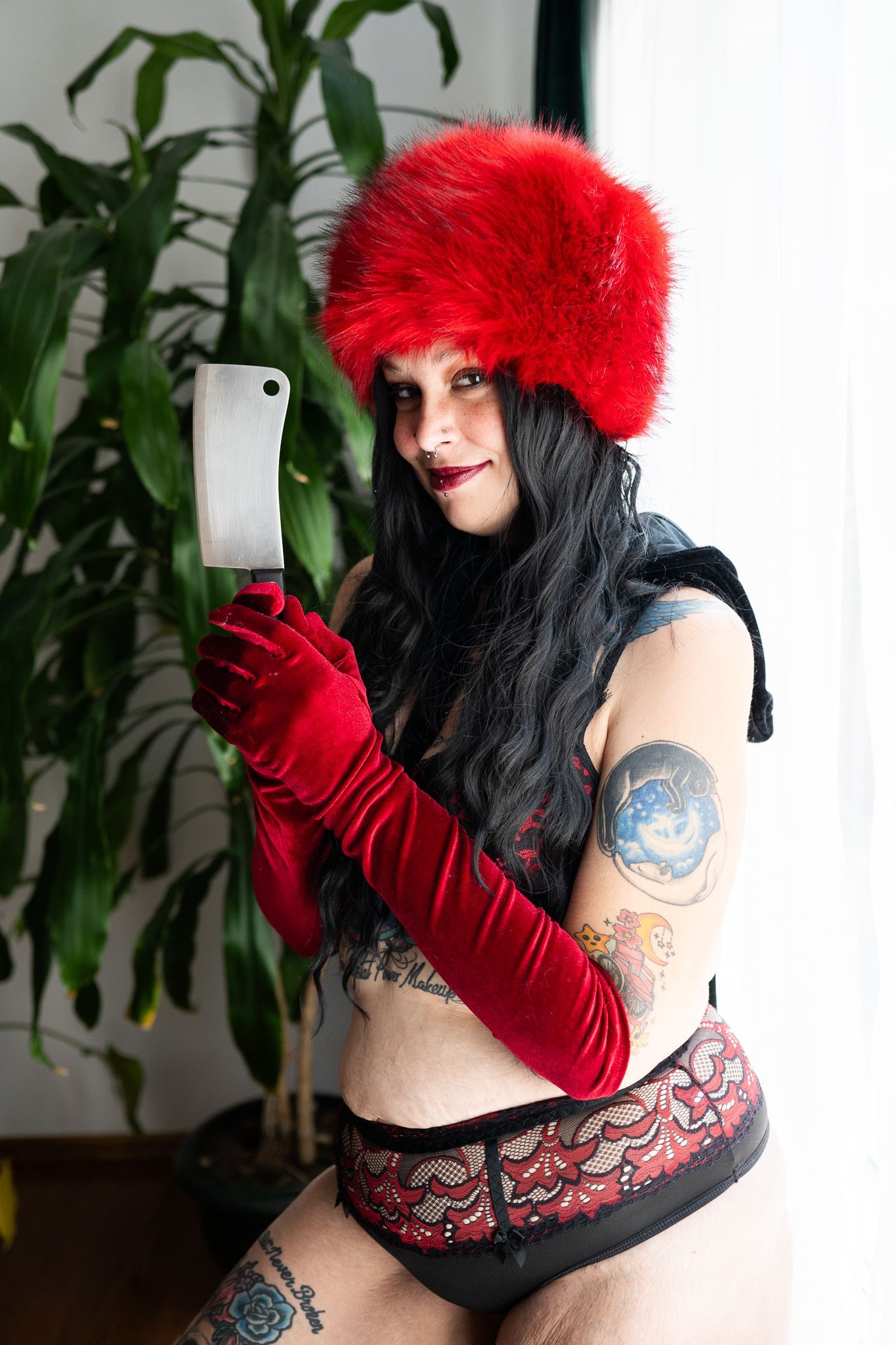 A woman in lingerie and a red hat is taking a selfie with her phone.