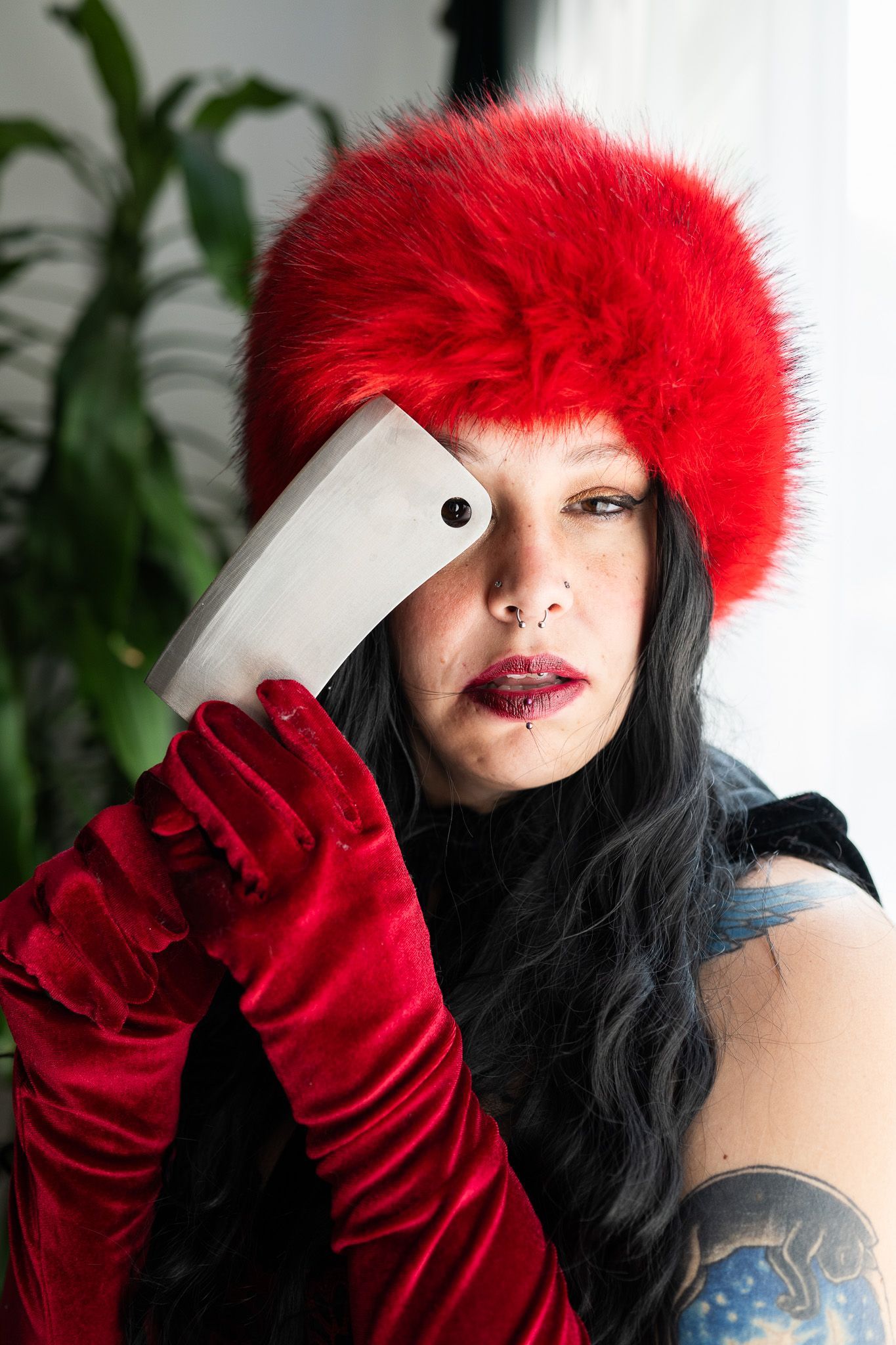 A woman wearing a red hat and red gloves is holding a cell phone.