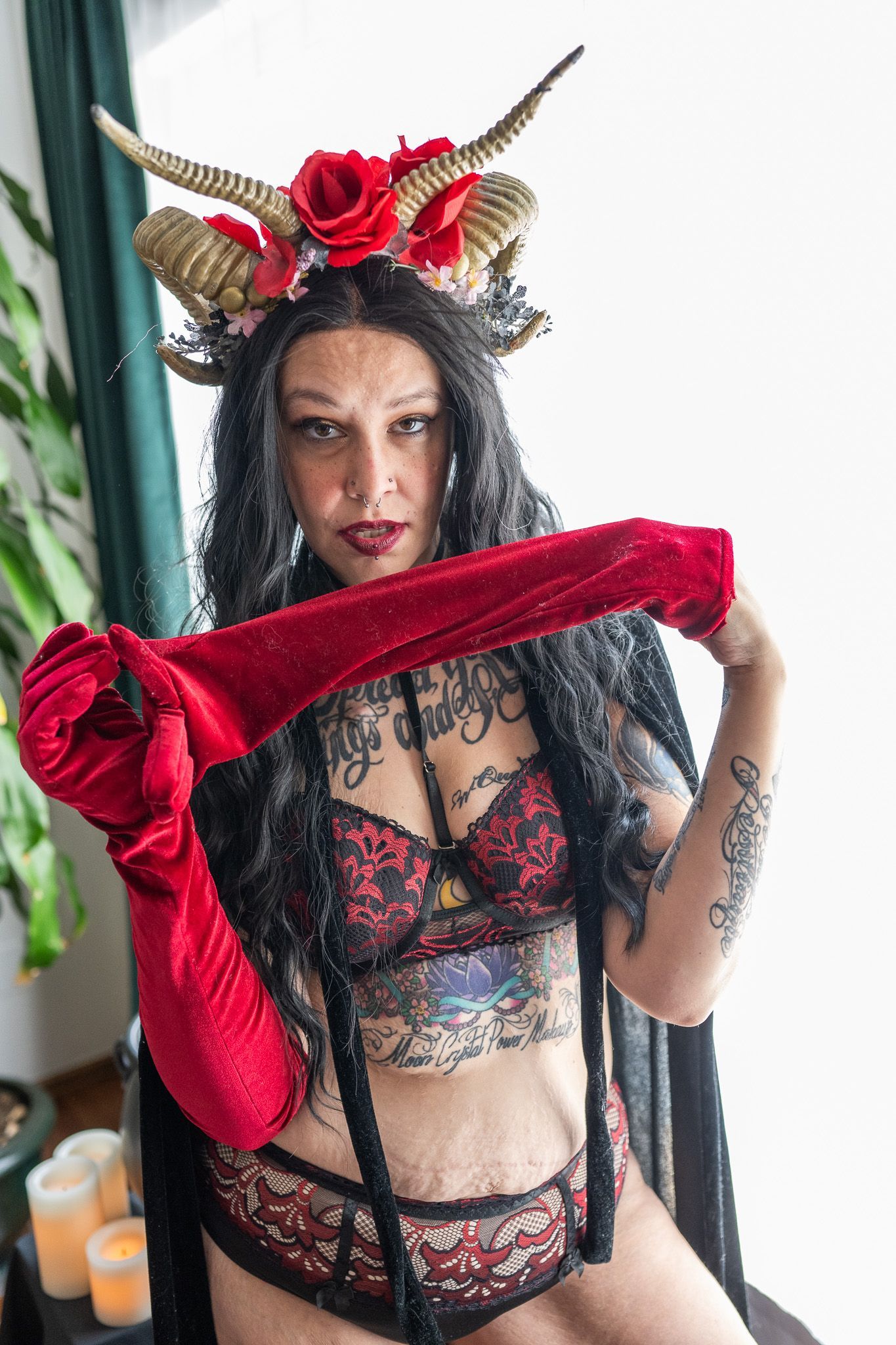 A woman in lingerie and a horned headband is holding a red glove.