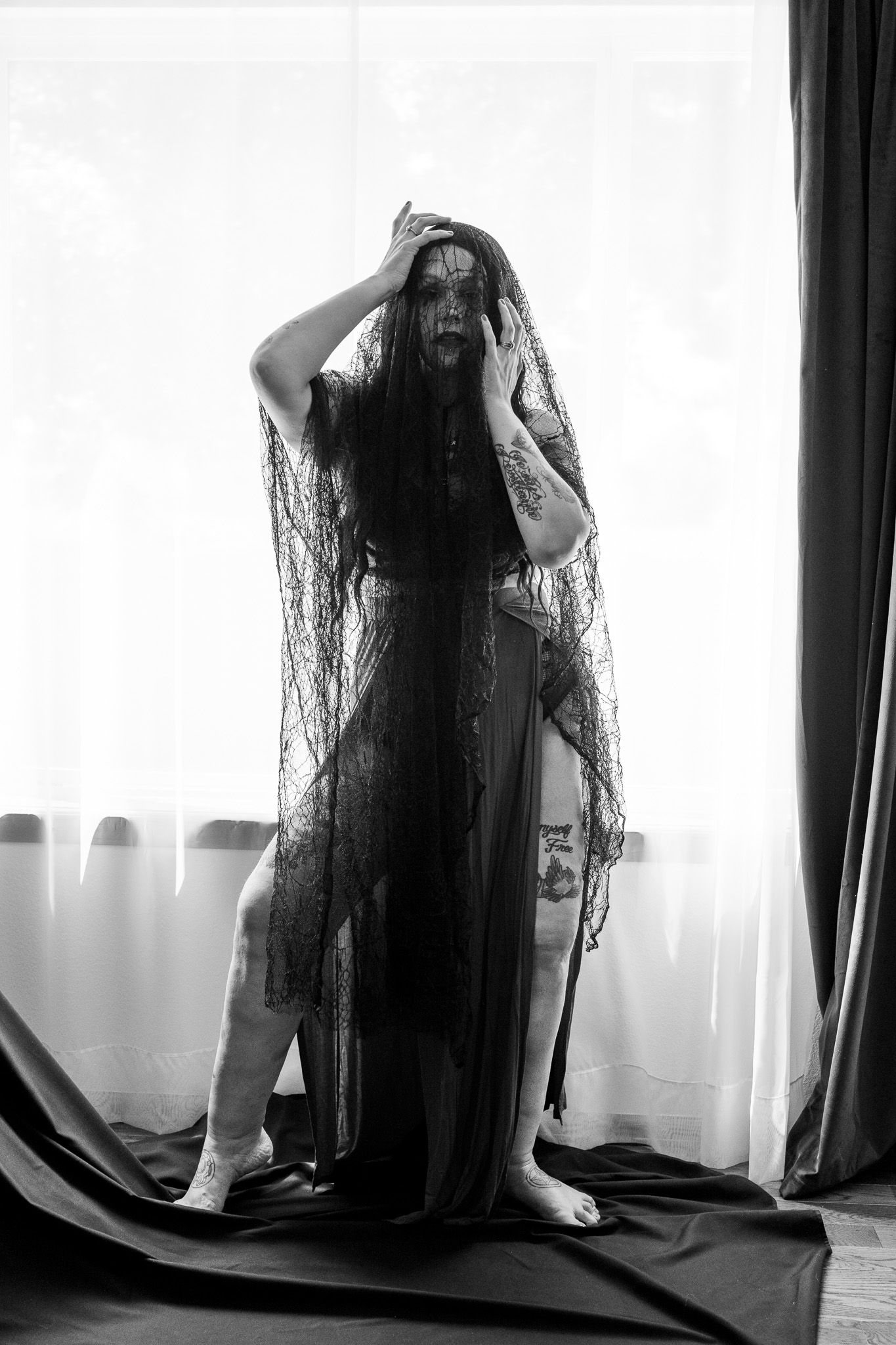A woman with very long hair is standing in front of a window.