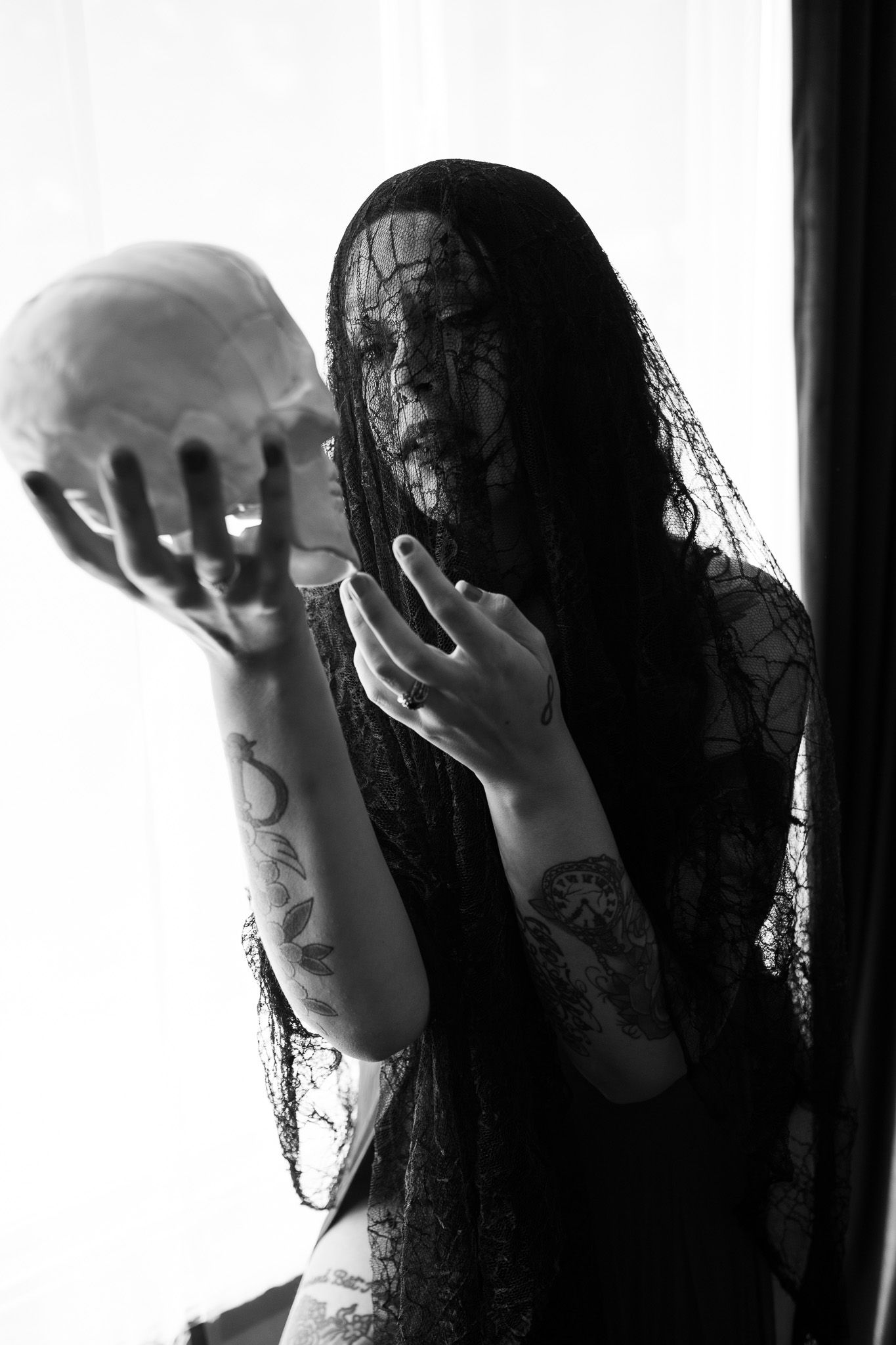 A woman with a veil on her face is holding a skull in her hands.