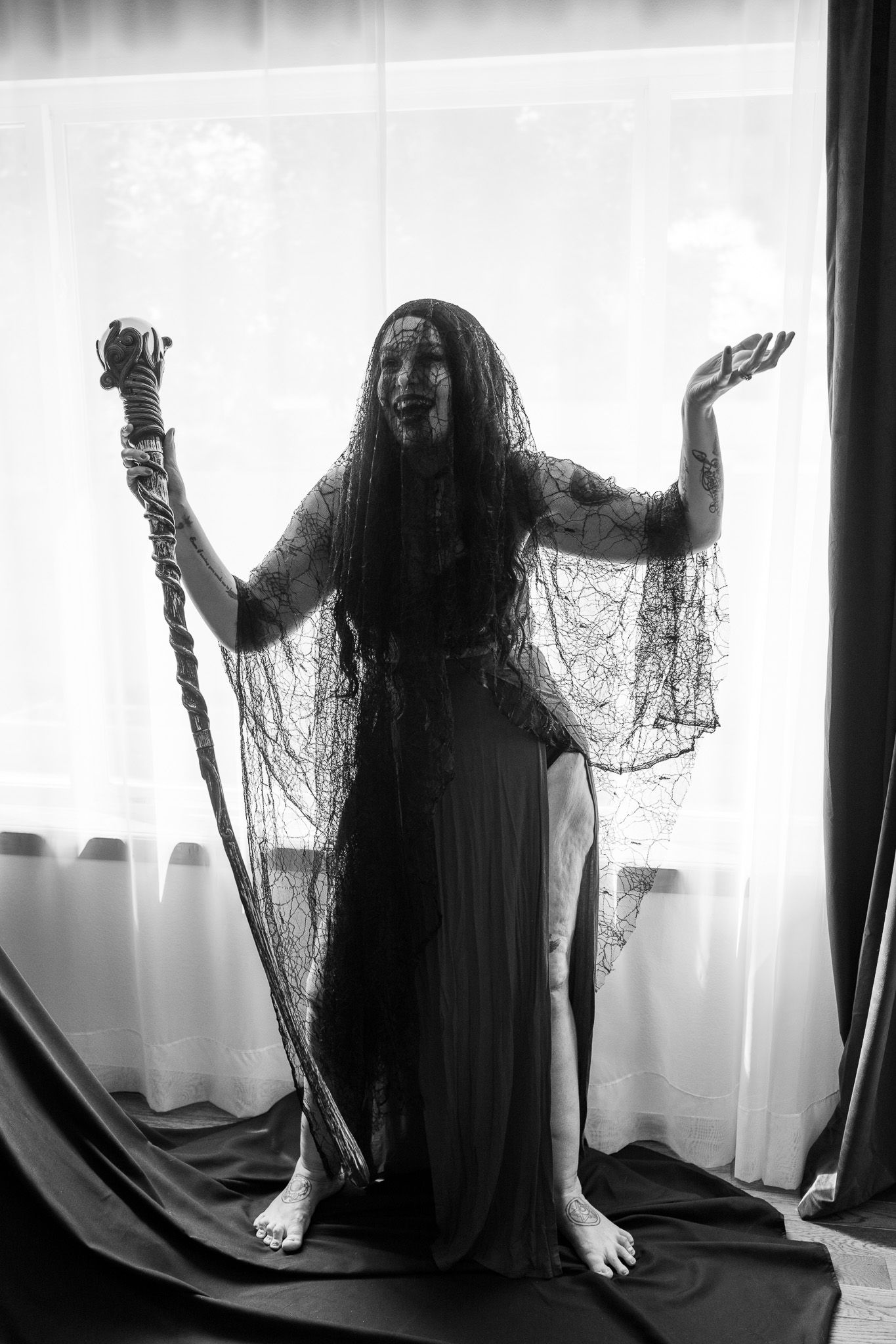 A black and white photo of a woman holding a chain in front of a window.
