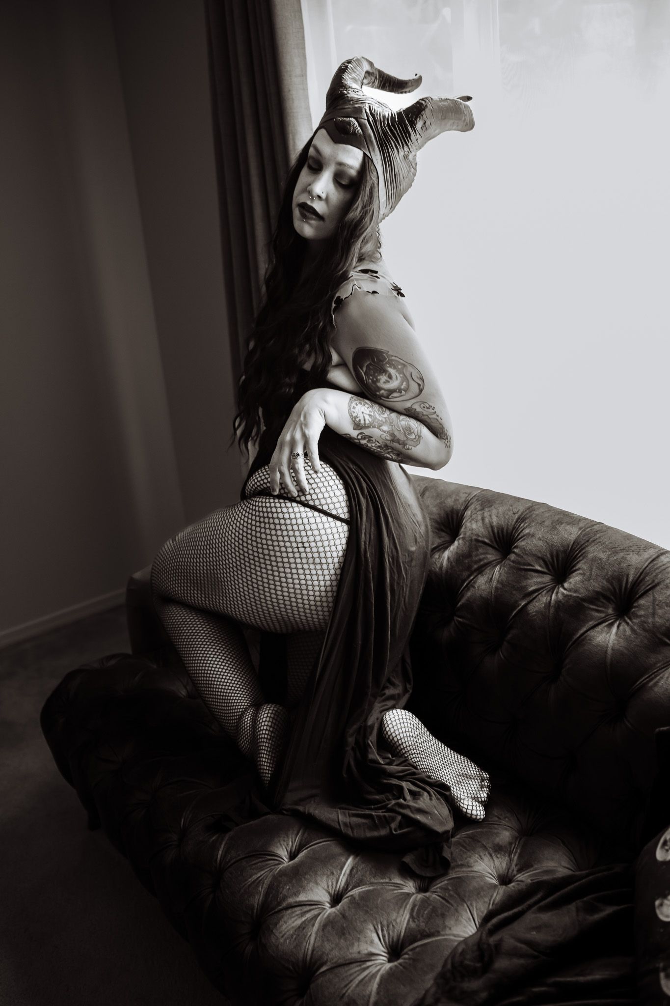 A black and white photo of a woman sitting on a couch.