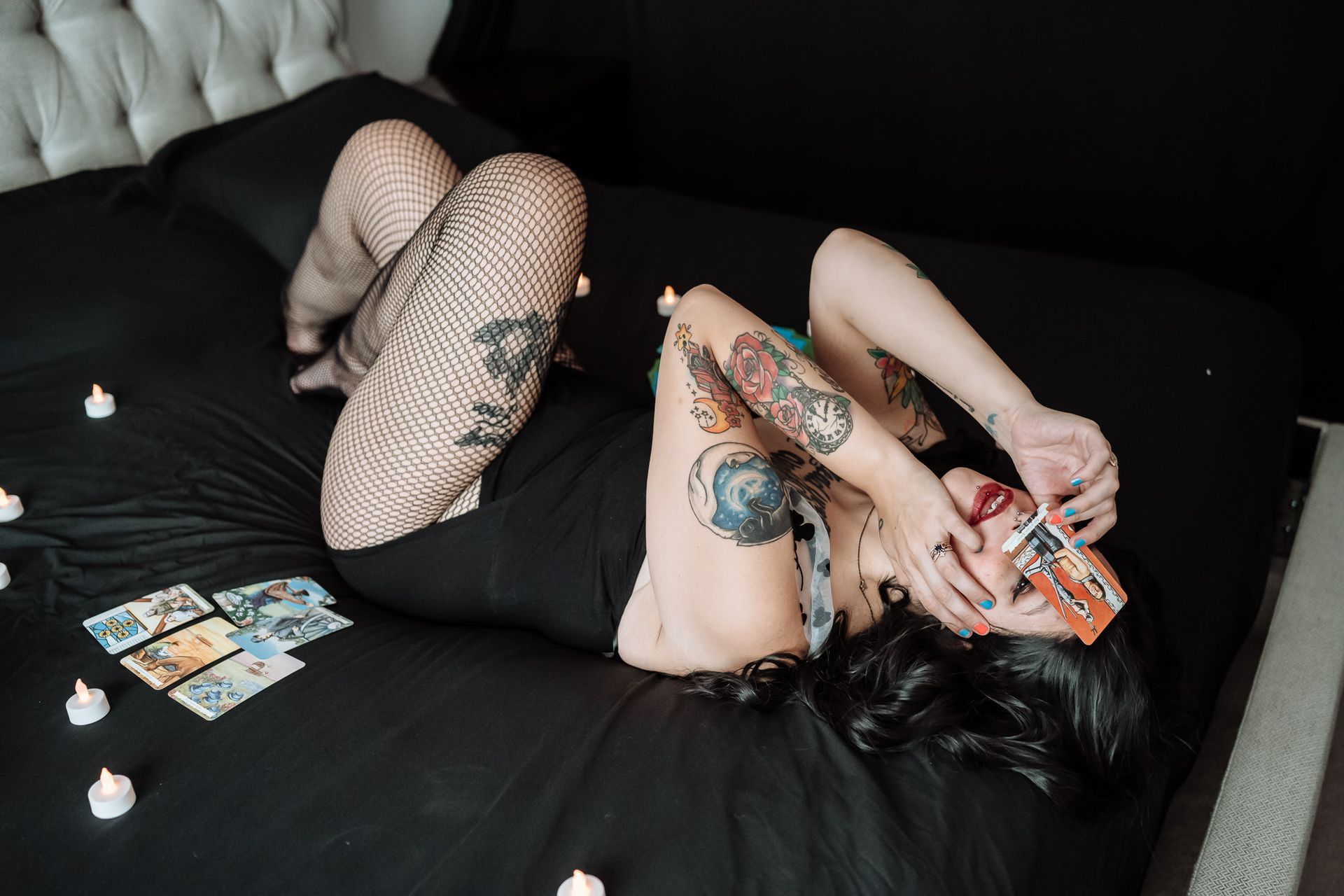 A woman is laying on a bed with candles and a book.
