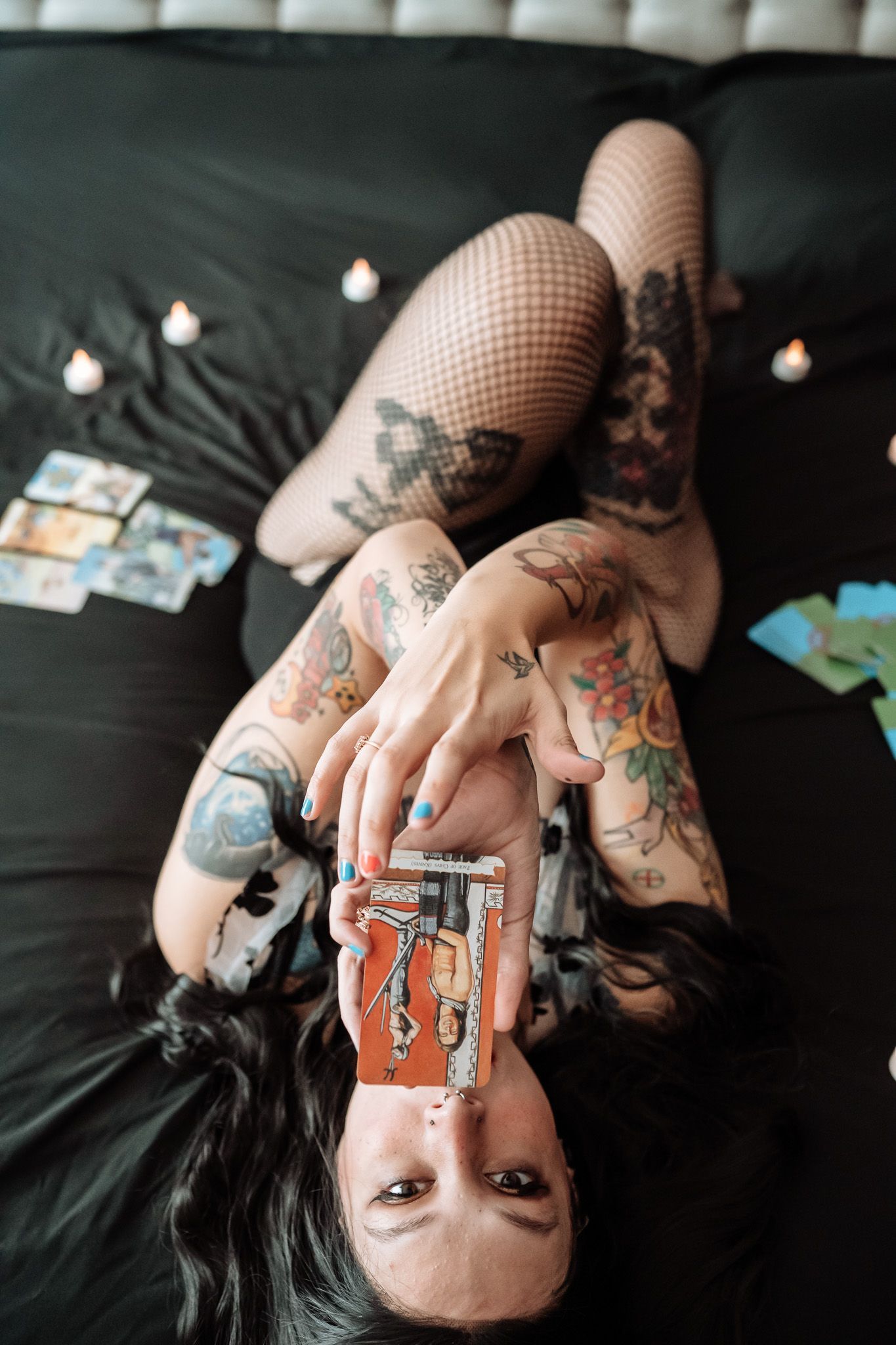 A woman is laying on a bed holding a tarot card.