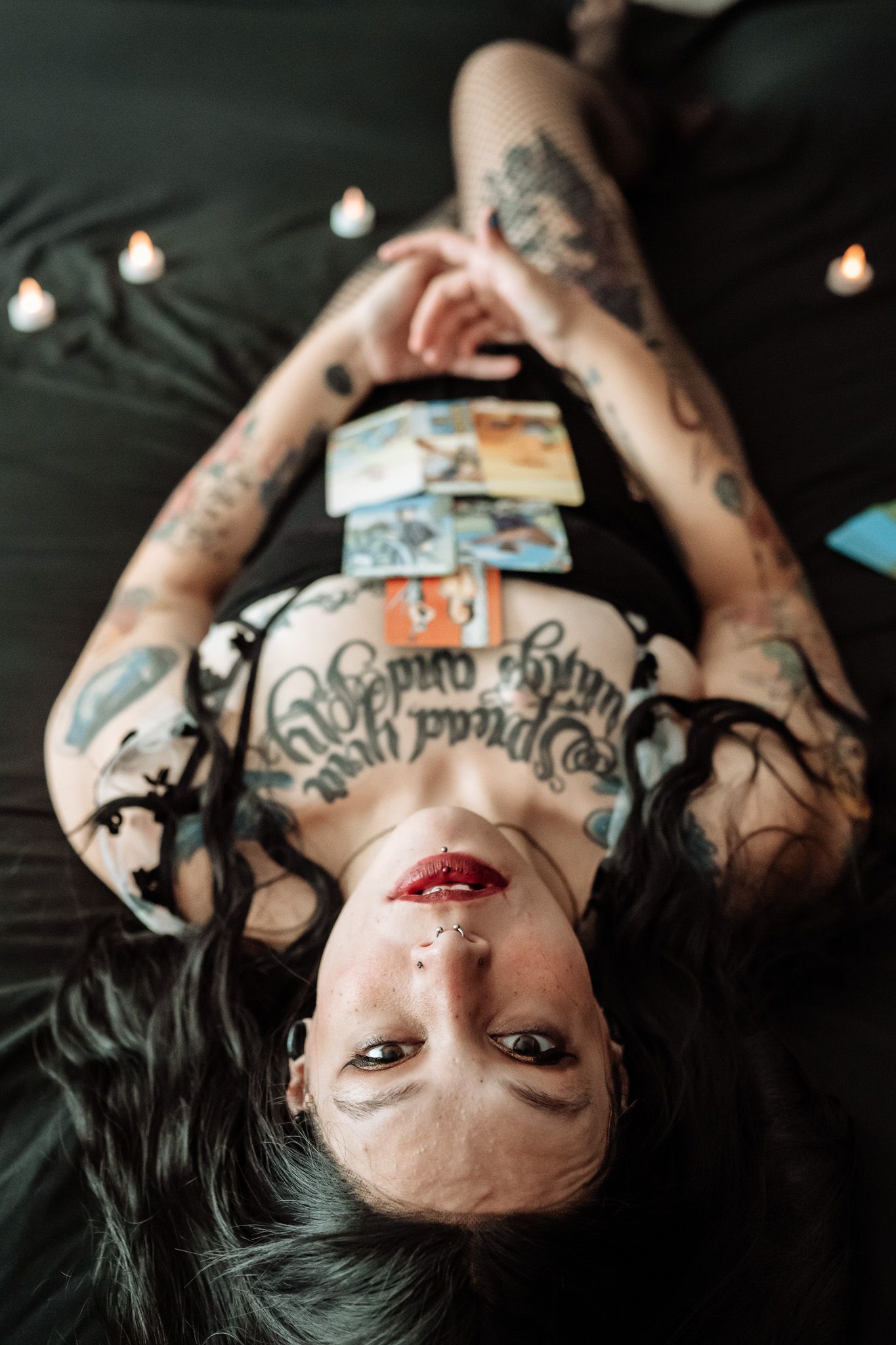 A woman with a lot of tattoos is laying on her back on a bed.