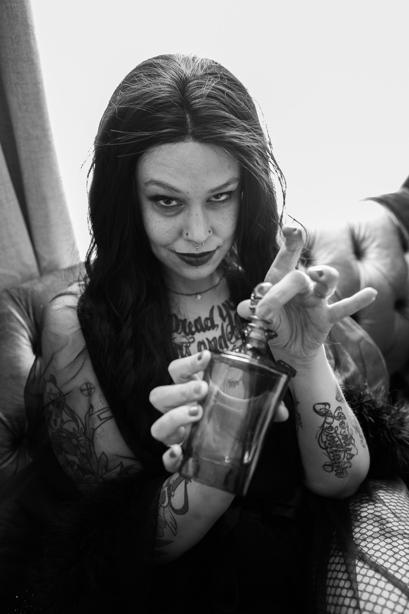 A black and white photo of a woman sitting on a couch holding a glass.