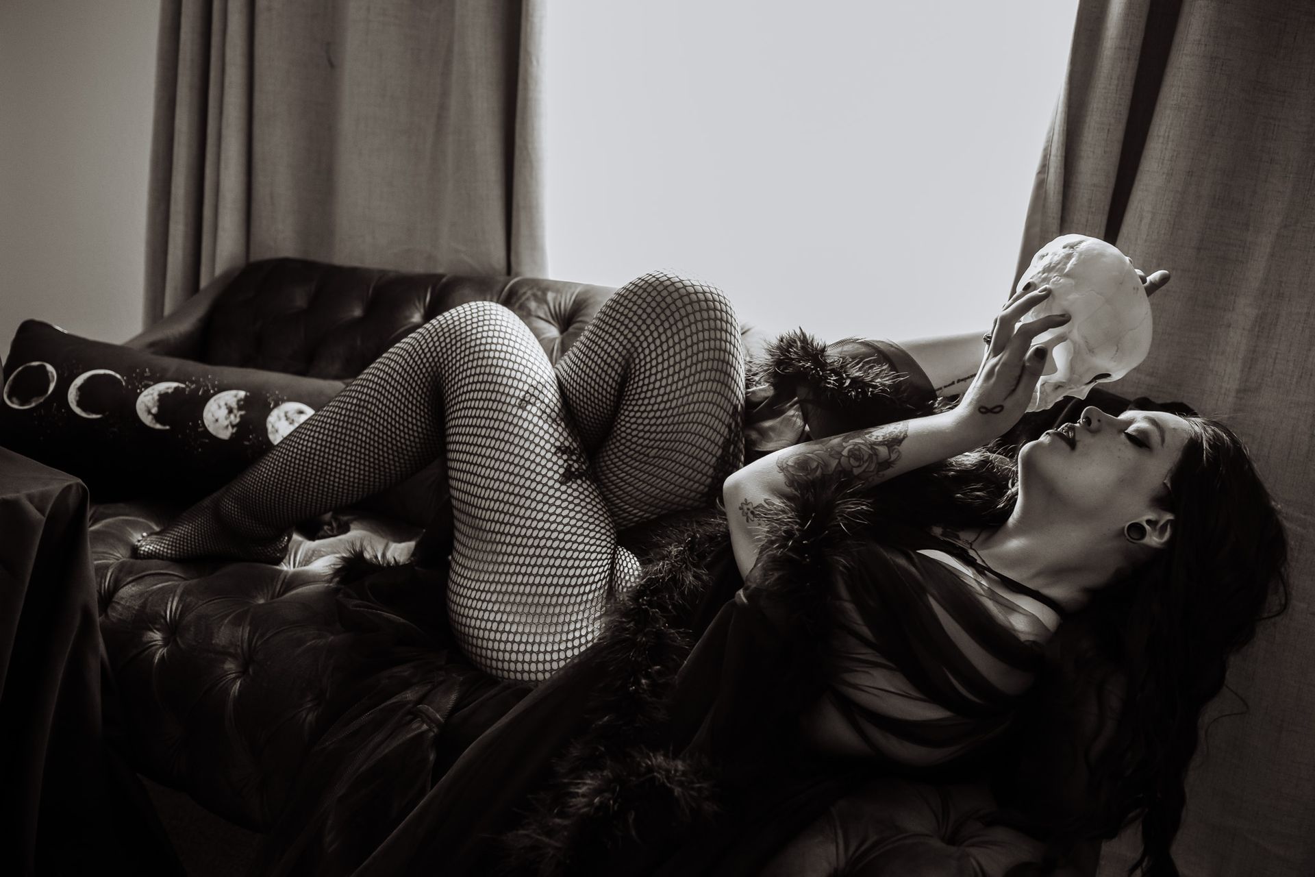A woman is laying on a couch with a skull in her hand.
