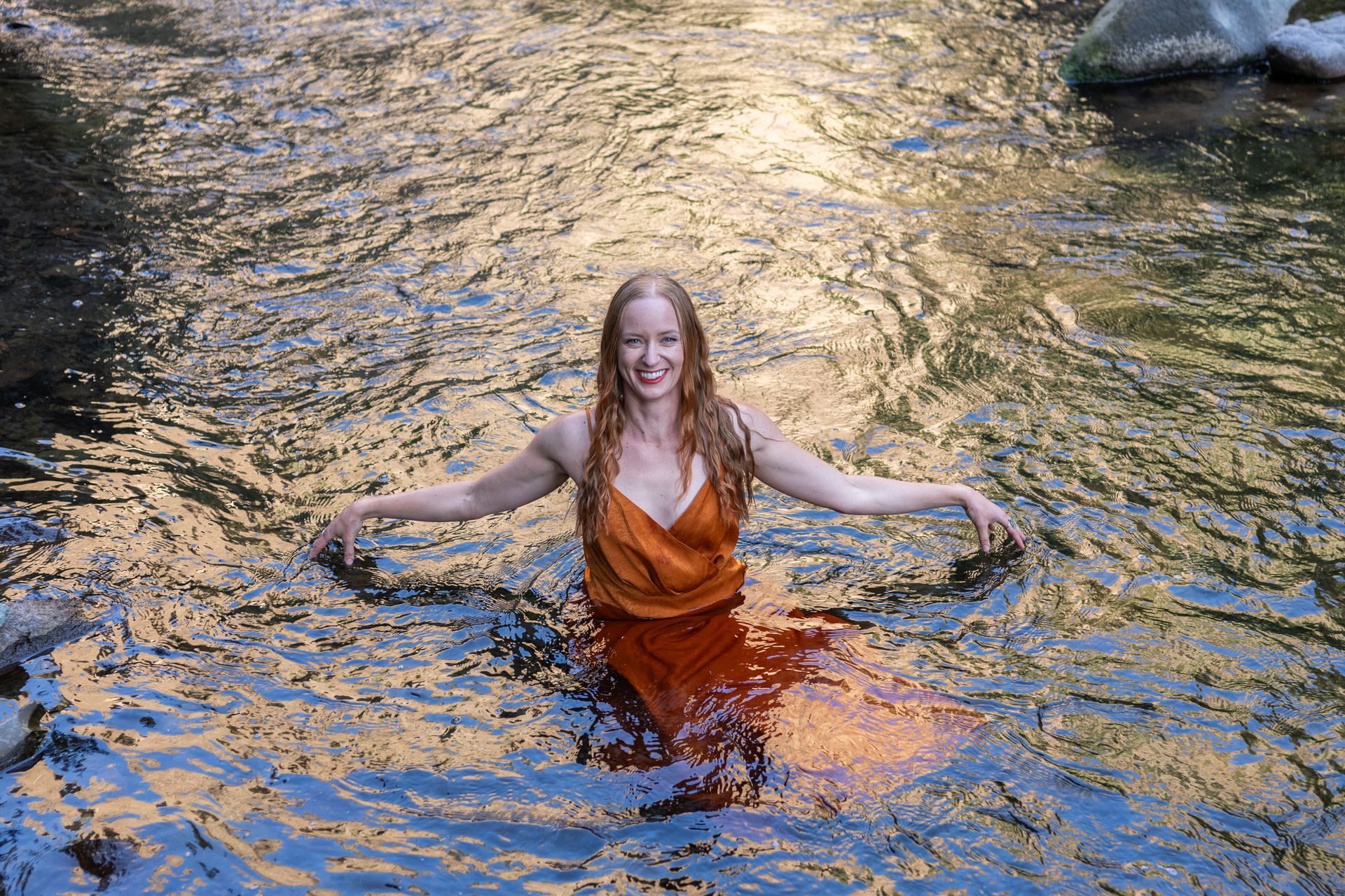 A woman in a dress is standing in the water.