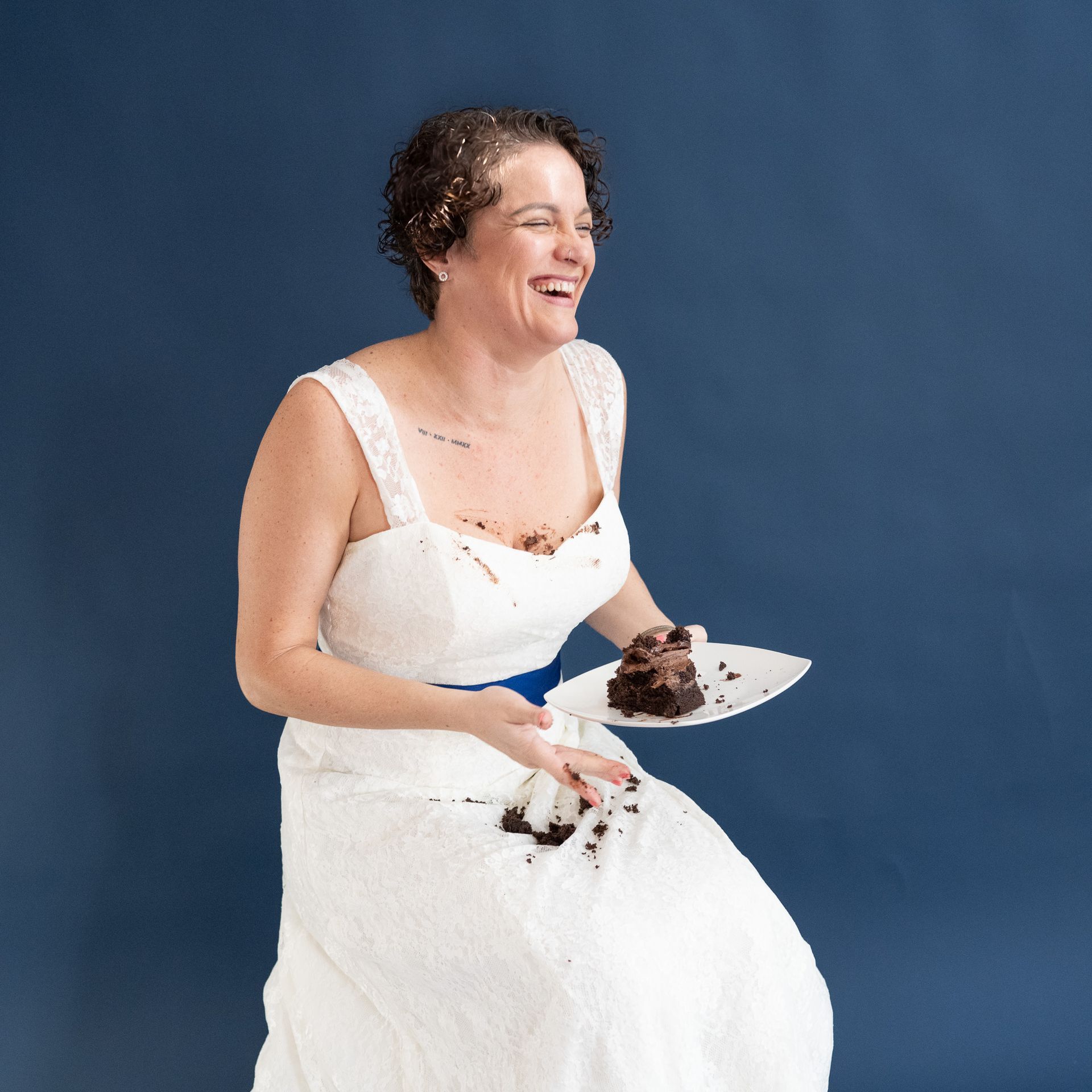 A woman in a white dress is holding a plate of cake