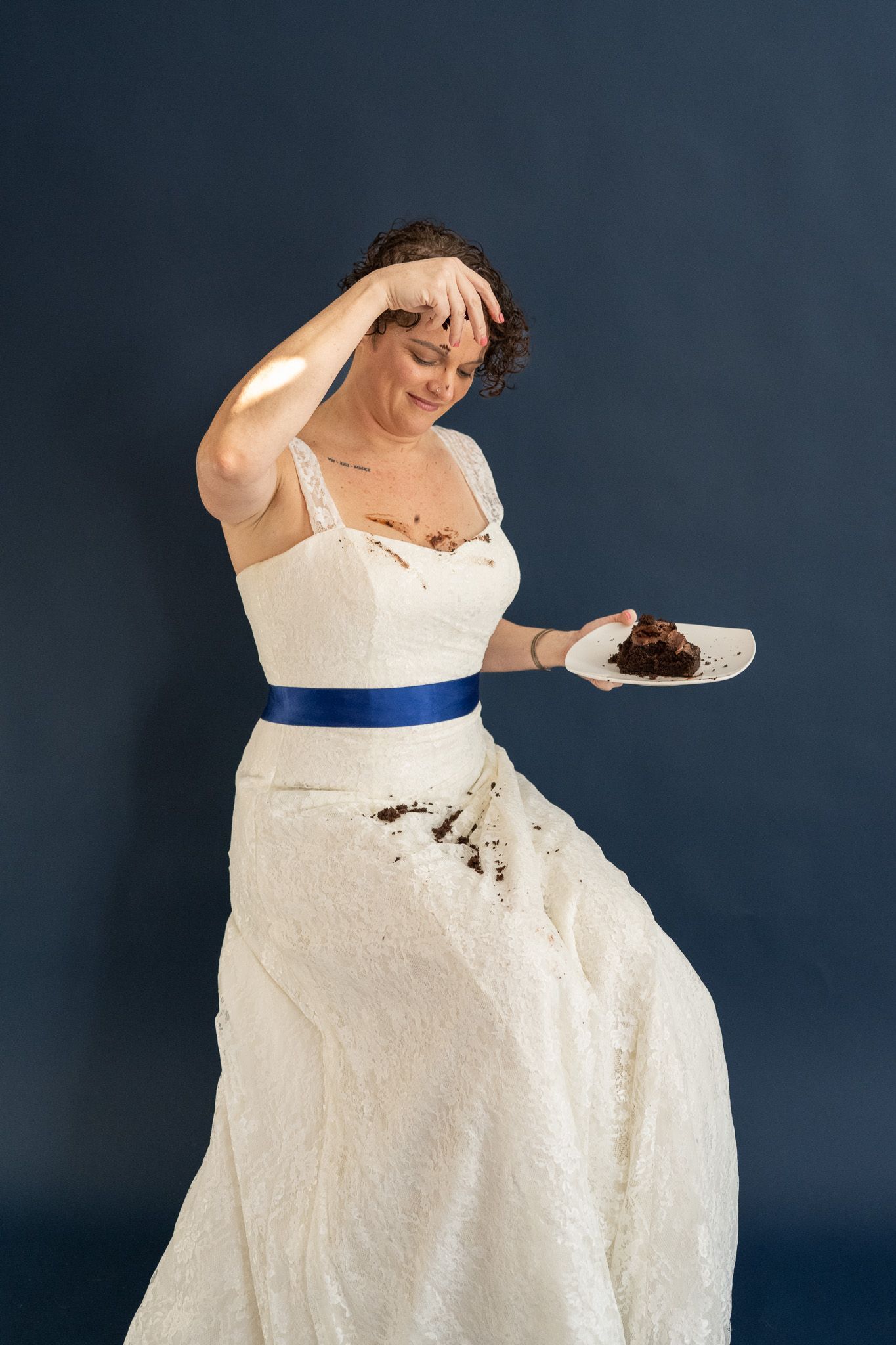 A woman in a wedding dress is holding a piece of cake