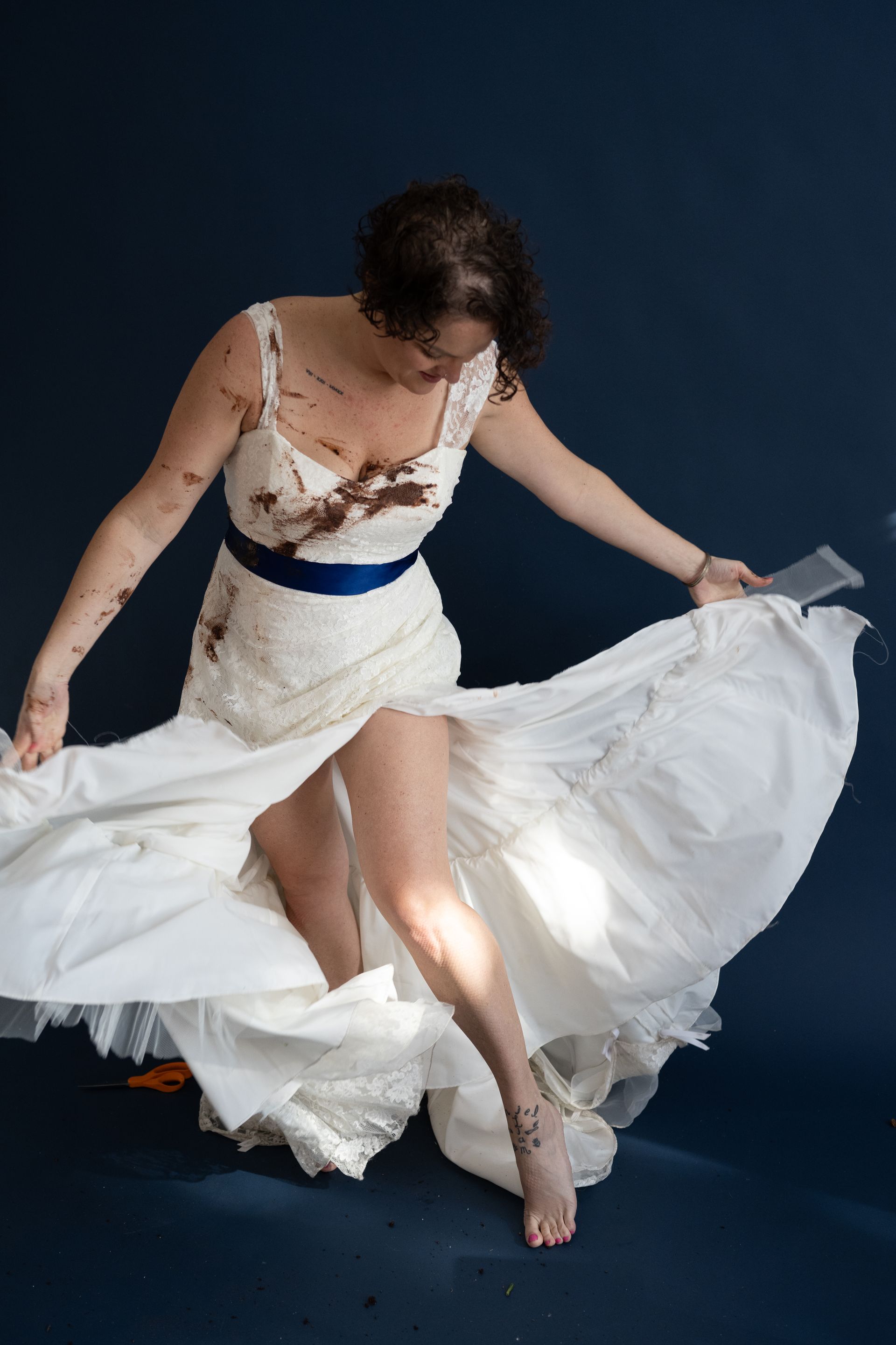 A woman in a white dress with a blue sash is dancing