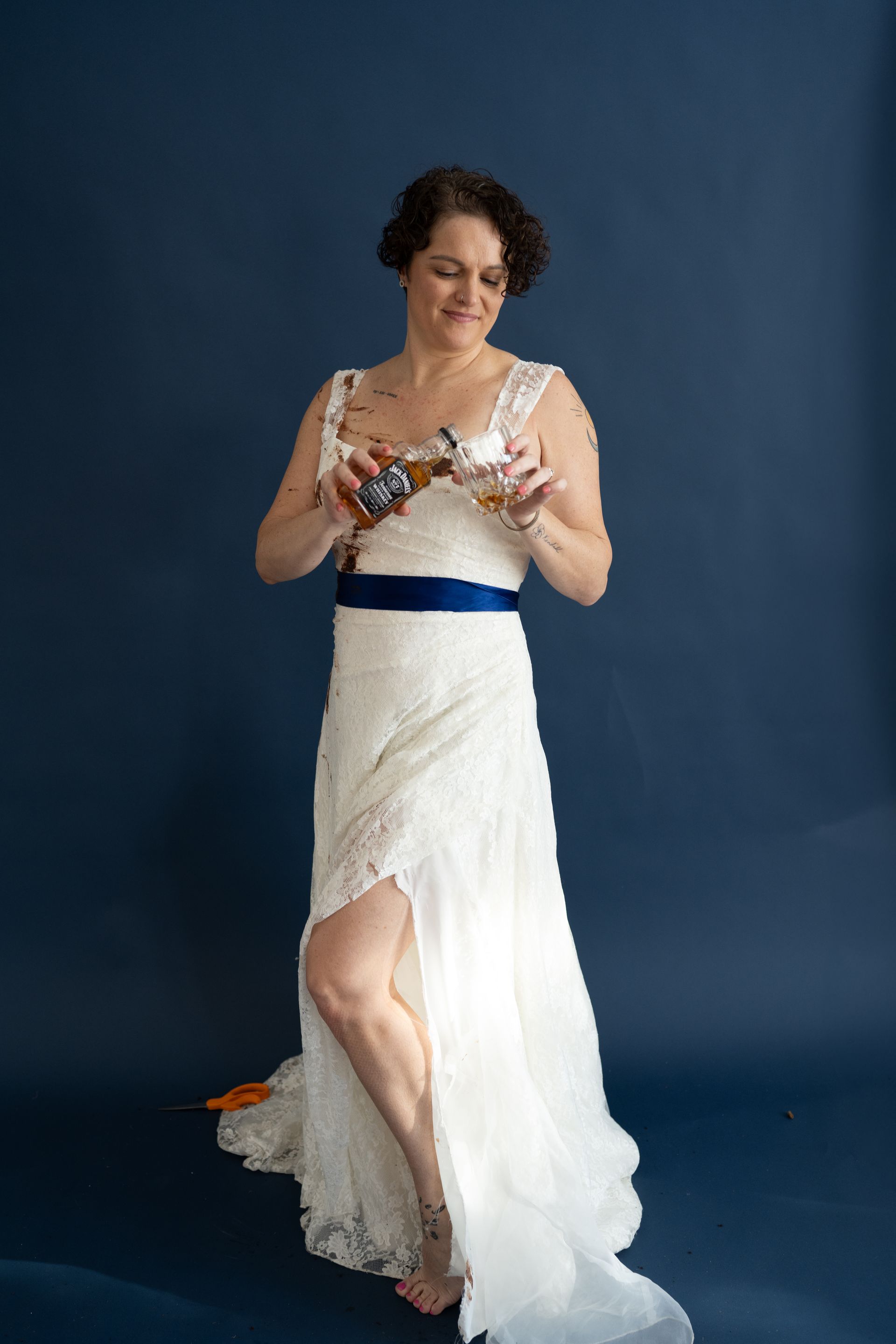 A woman in a white dress is holding a bottle of wine.