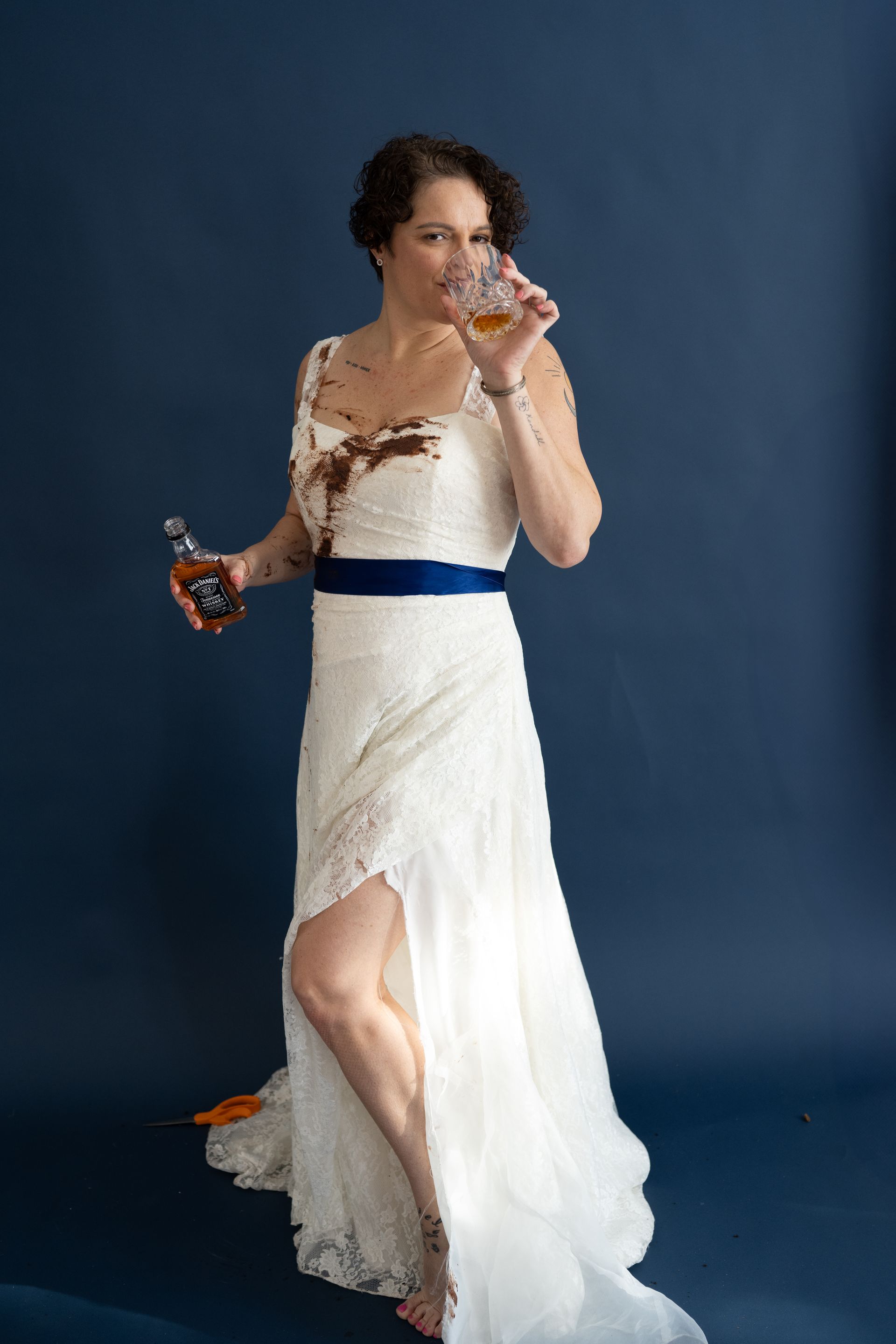 A woman in a wedding dress is drinking a glass of whiskey
