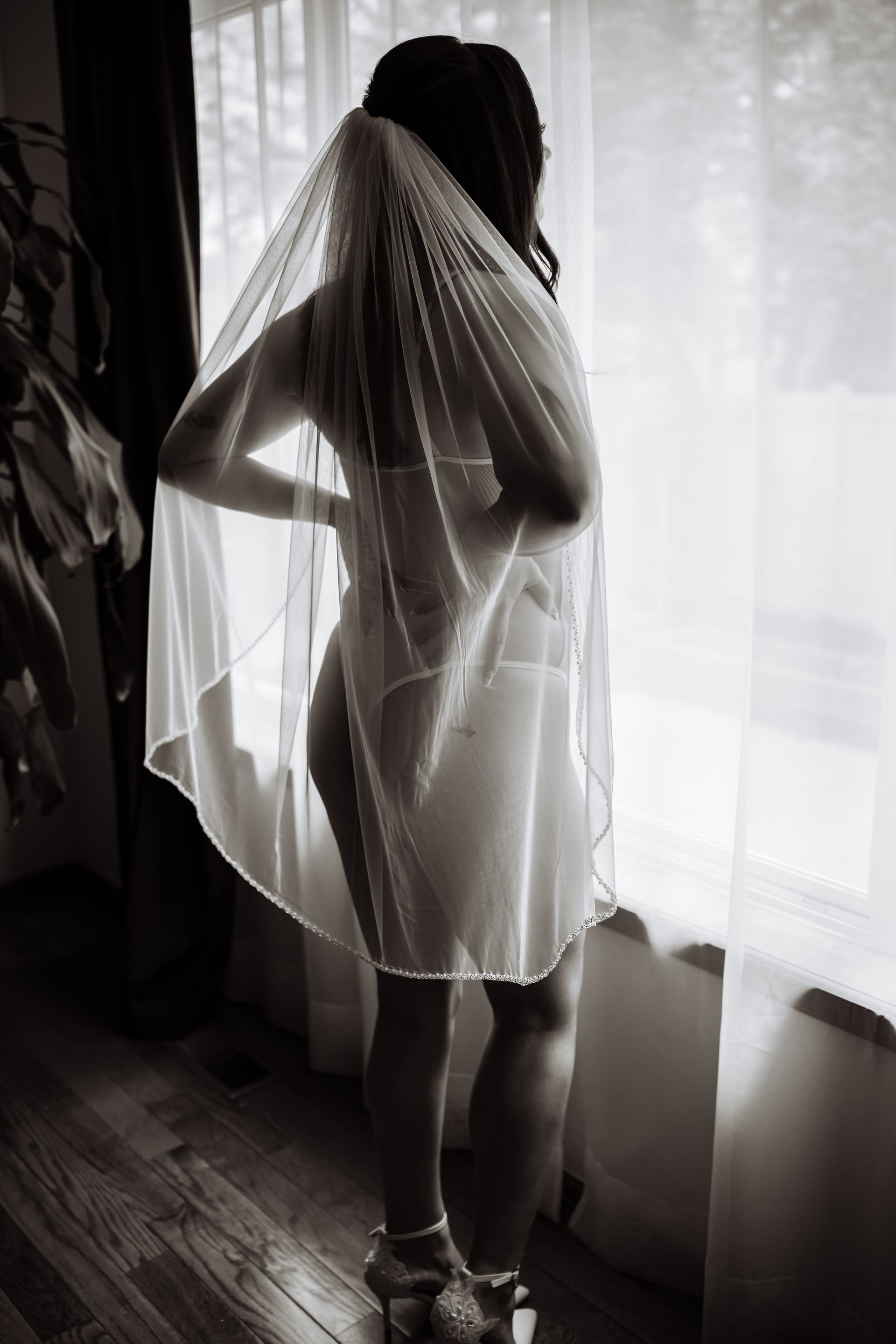 A woman in a veil is standing in front of a window.