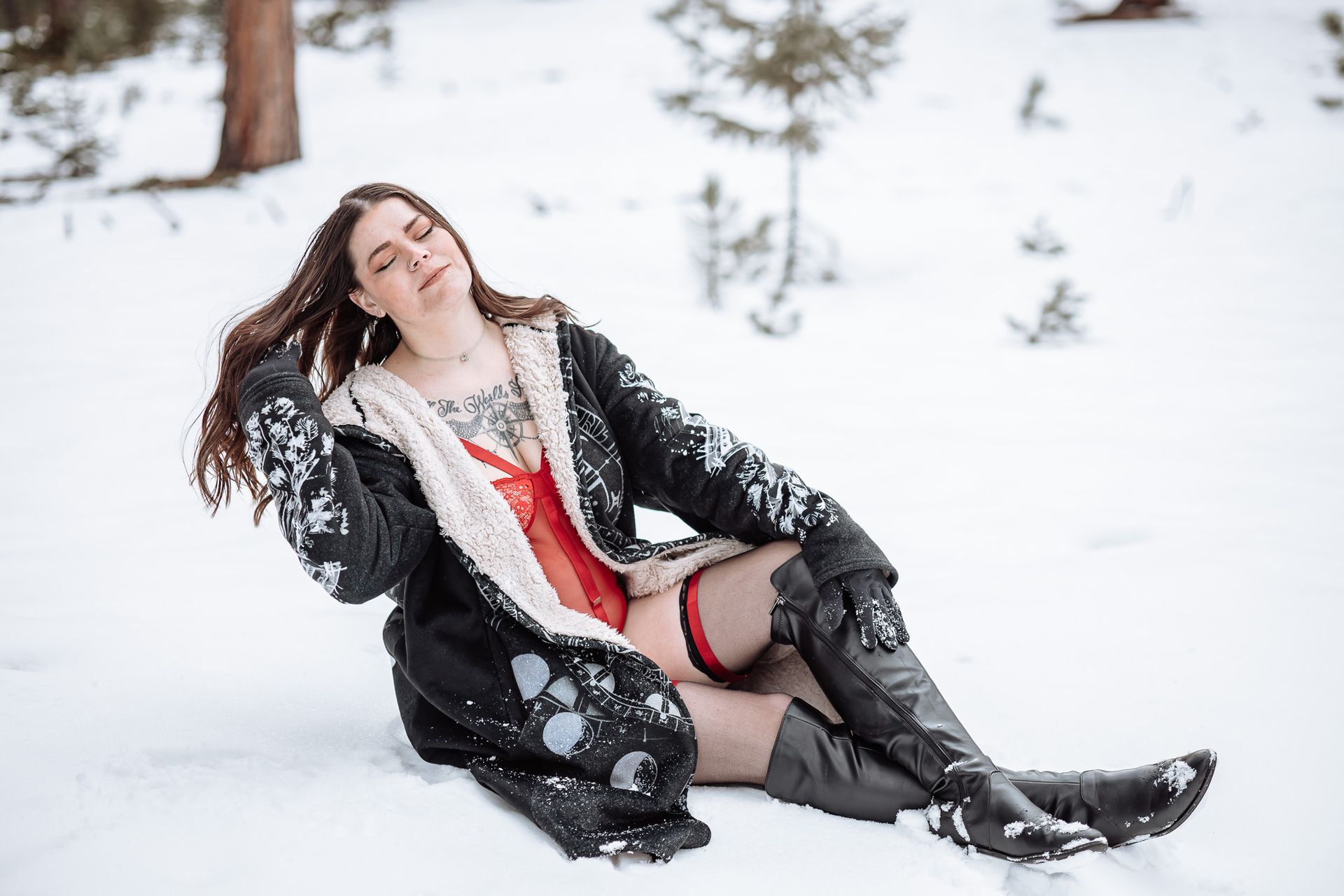 A woman is laying on the ground in the snow.