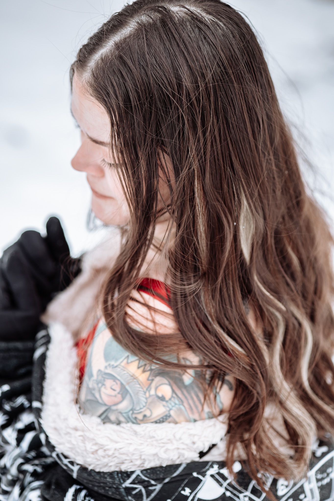 A woman with braids is holding a doll in her arms in the snow.
