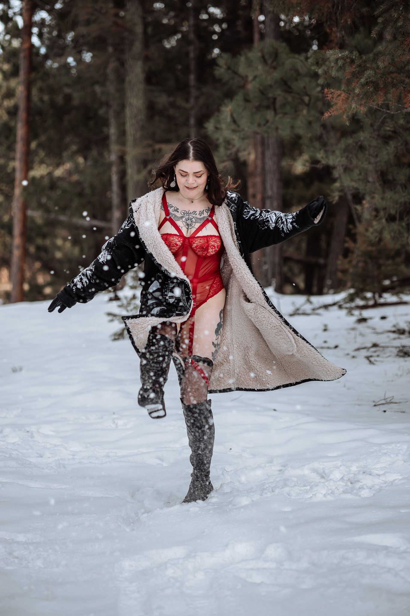 A woman in lingerie is walking through the snow in the woods.