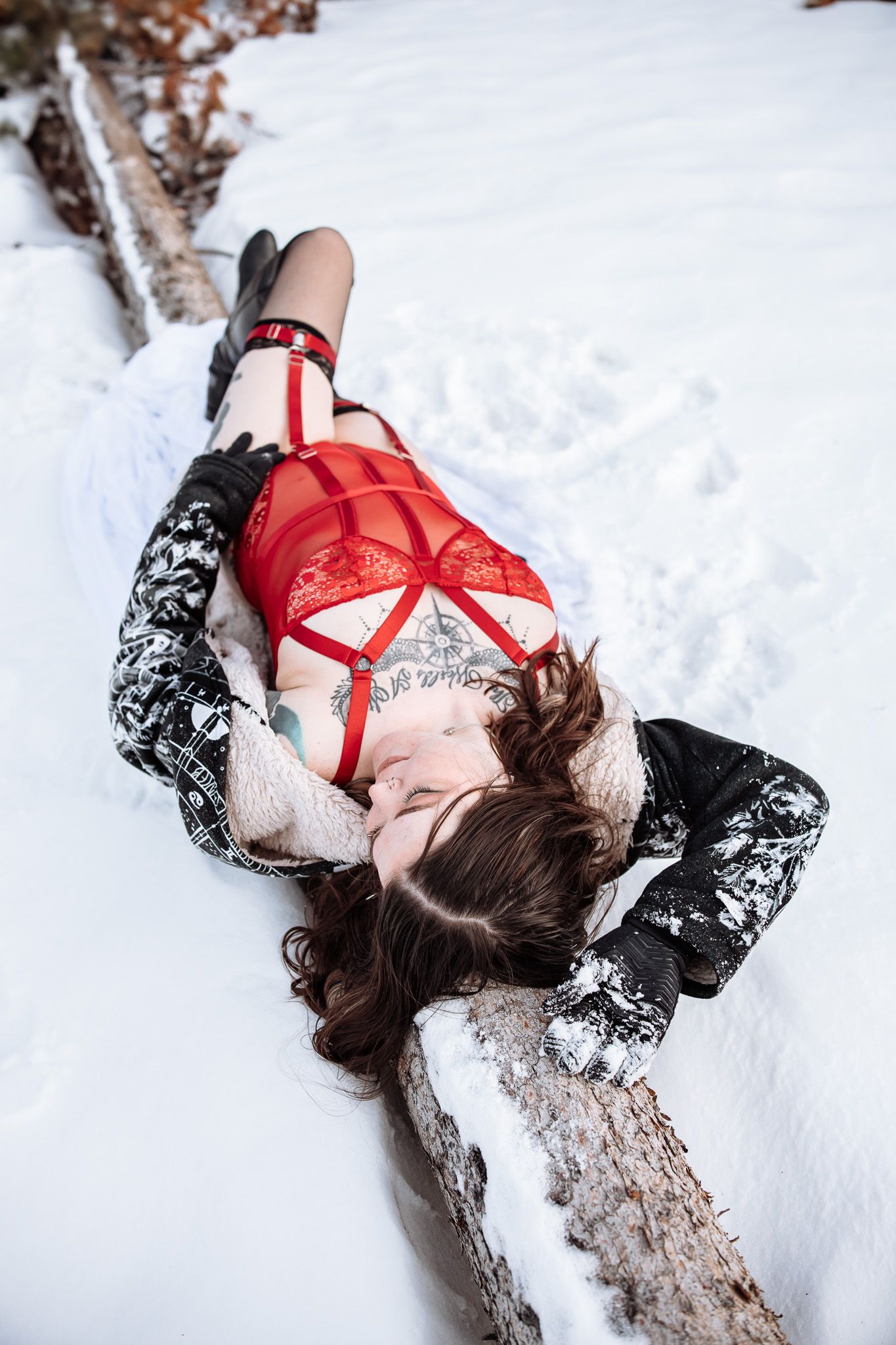 A woman in red lingerie is laying in the snow.