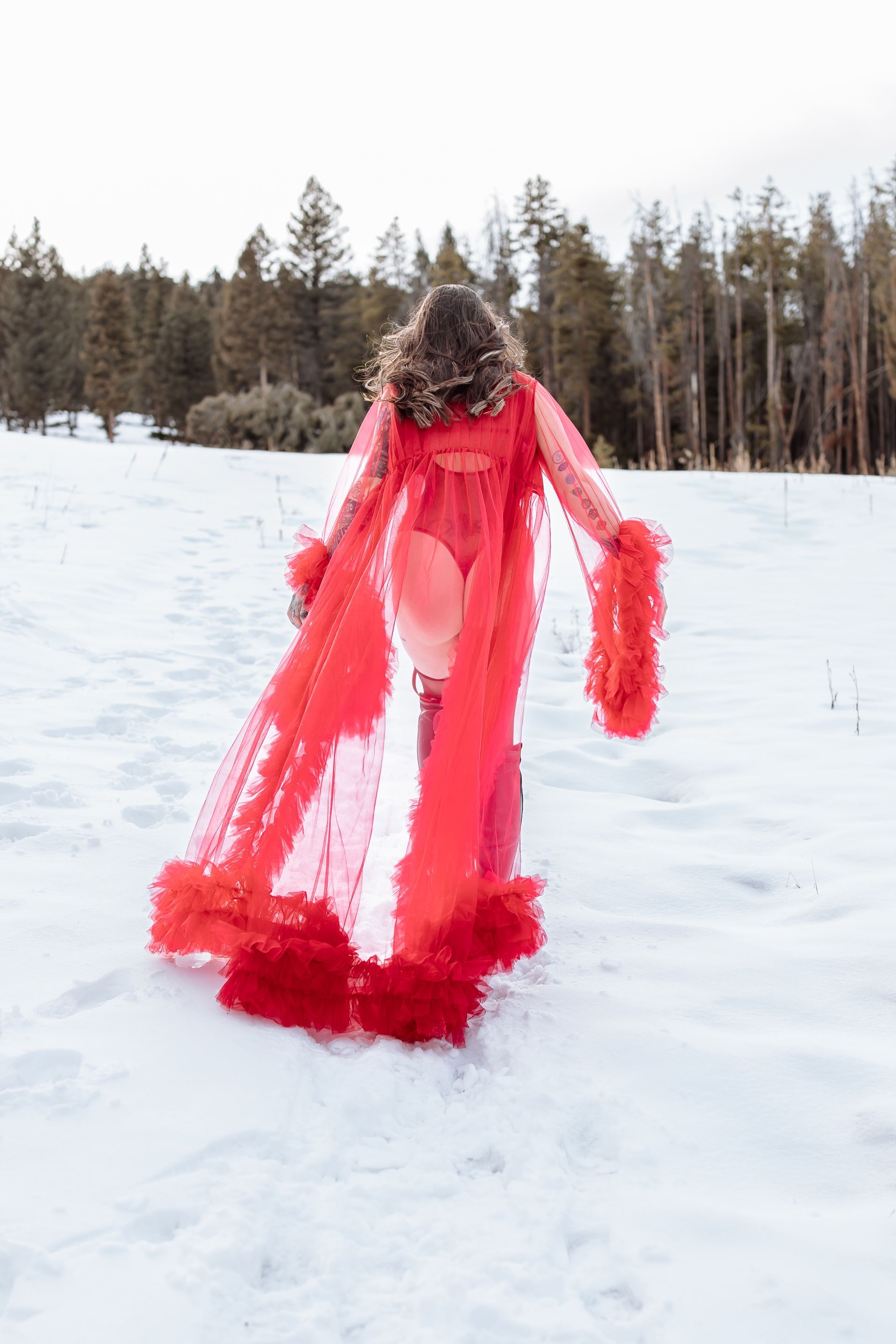 A woman in a red robe is walking through the snow.