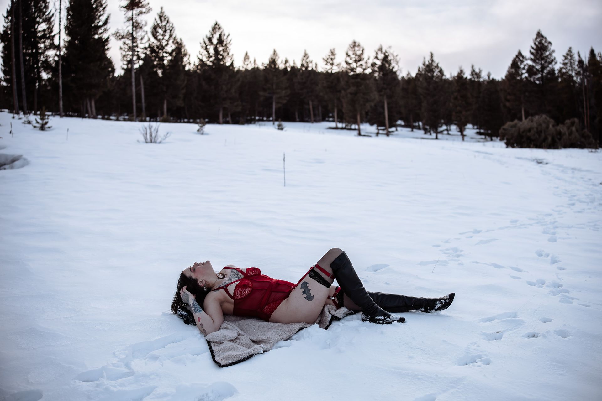 A woman in a red dress is laying in the snow.